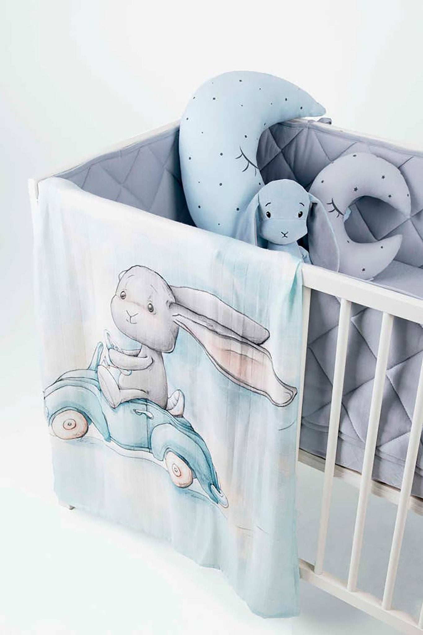 A baby is laying inside a crib staying warm inside the Great Day For a Ride Bamboo Swaddle - L'Atelier Global