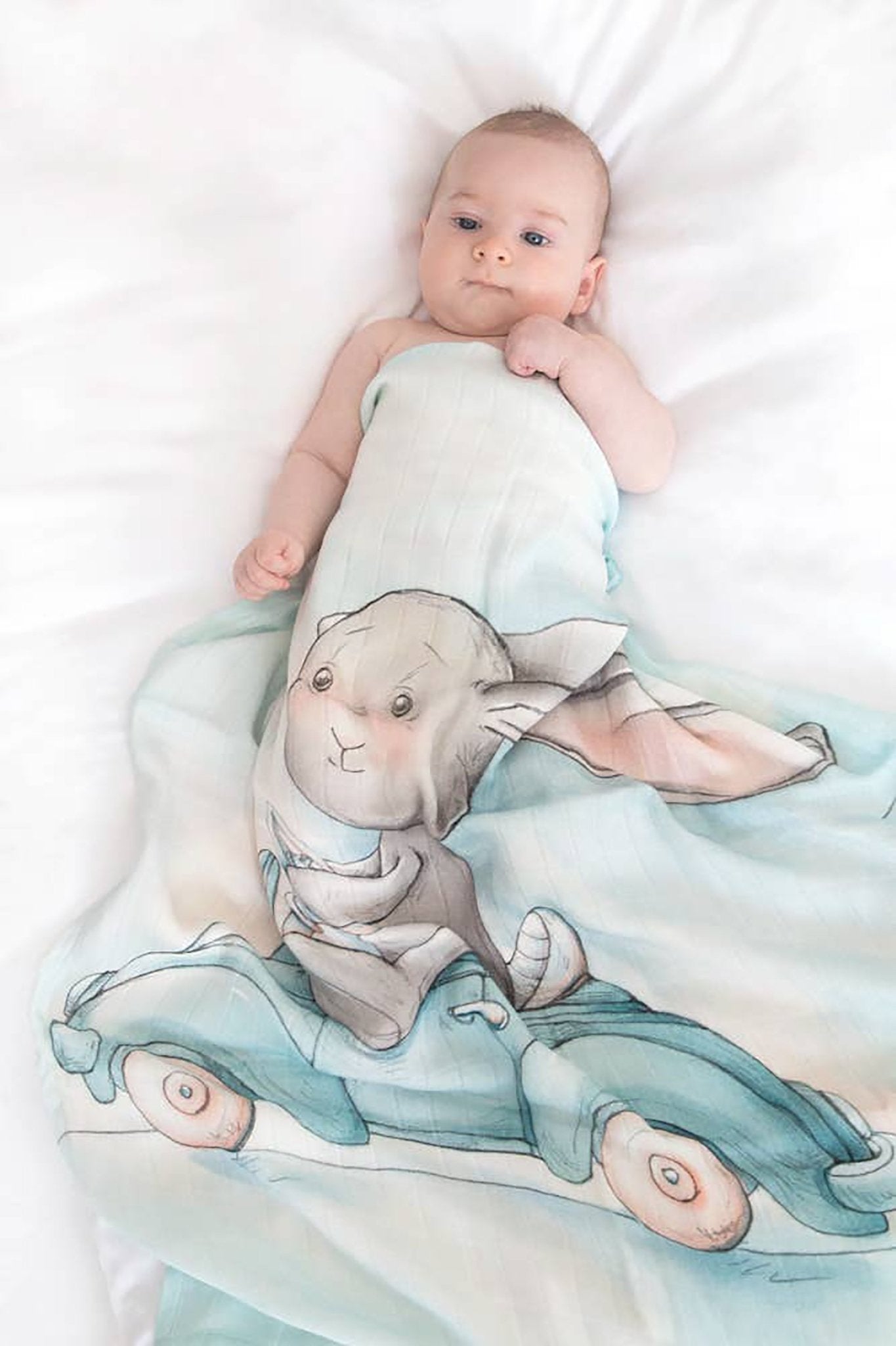 A baby is laying inside a crib staying warm inside the Great Day For a Ride Bamboo Swaddle - L'Atelier Global