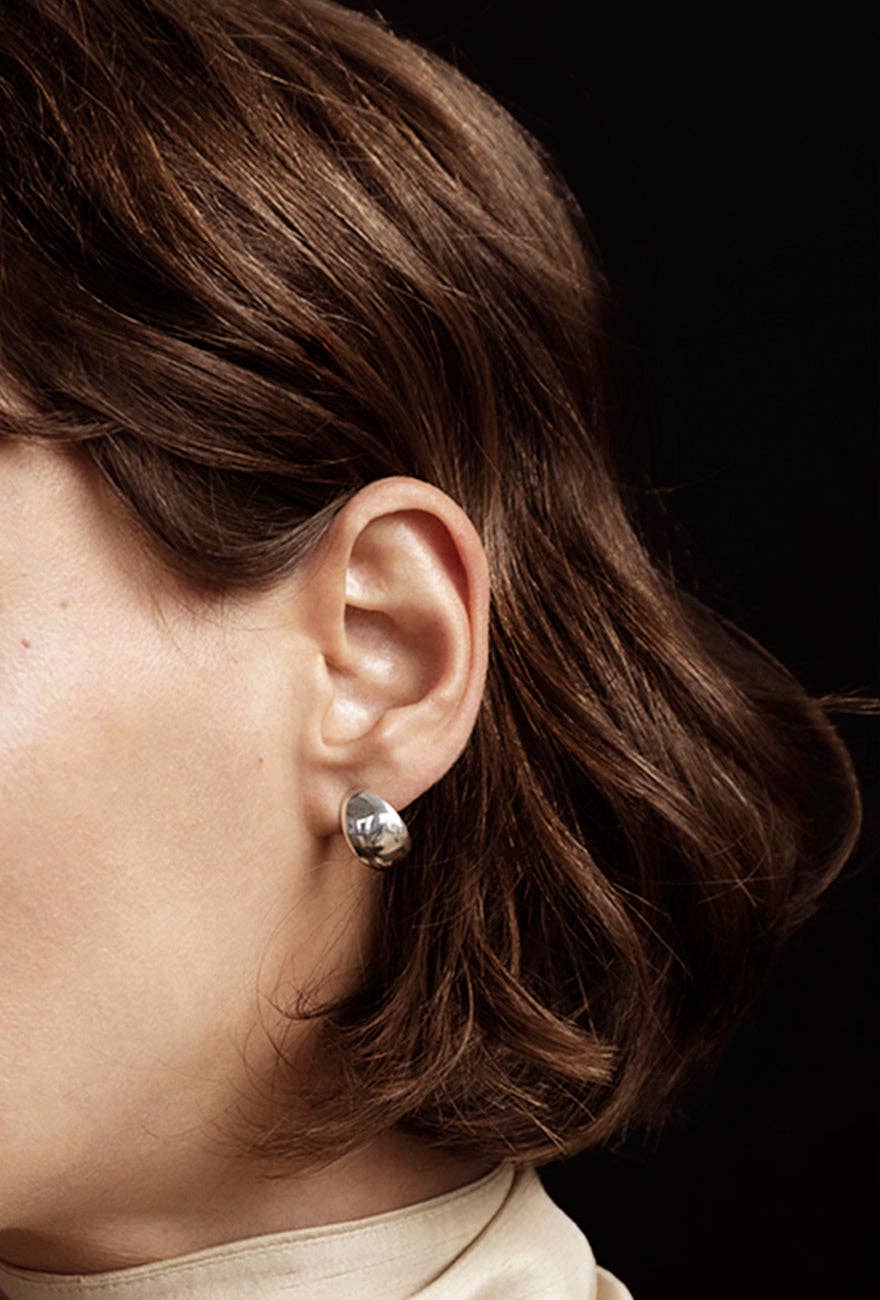 Huggie Earrings Sterling Silver is worn by a model showing her left ear. The earring closely hugs the ear.
