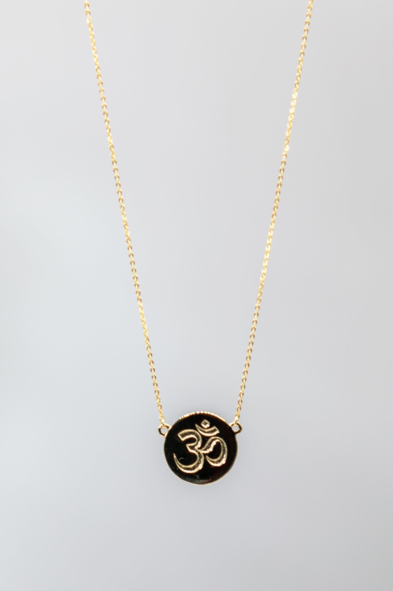 Irish Inner Peace Gold Necklace on a gray background - L'Atelier Global