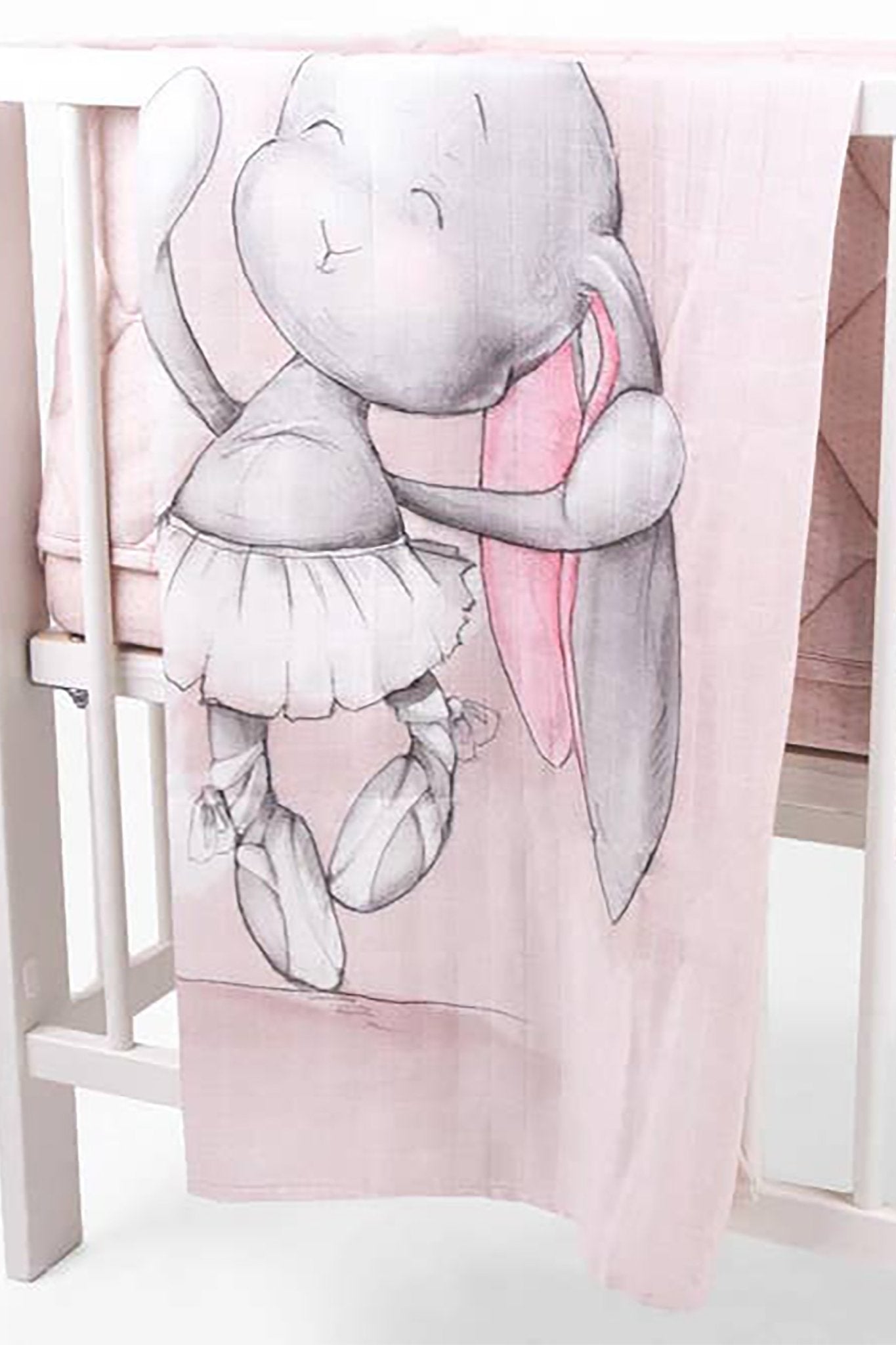A baby is laying inside a crib staying warm inside the Joyful Ballerina Bamboo Swaddle - L'Atelier Global
