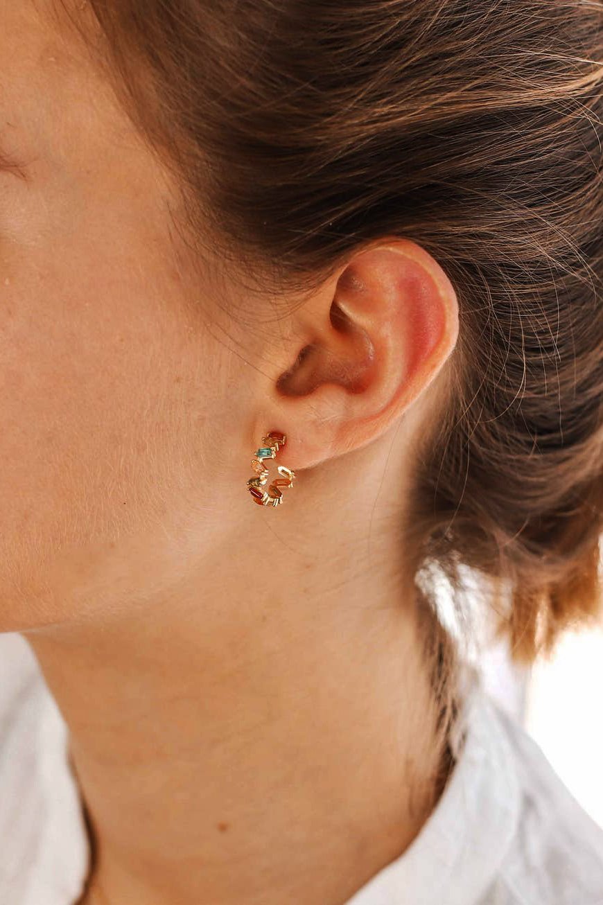 Close up image of the La Concha Hoop Earring in gold on a female model's left ear. You can see the subtle zig zag silhouette.