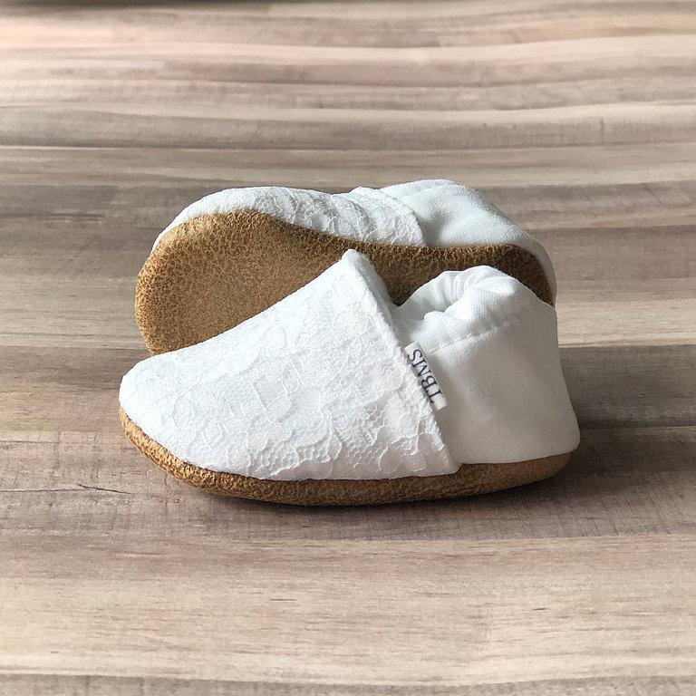 Lacey White Cotton Canvas Moccasins showing outsoles on a soft ash hued wood table