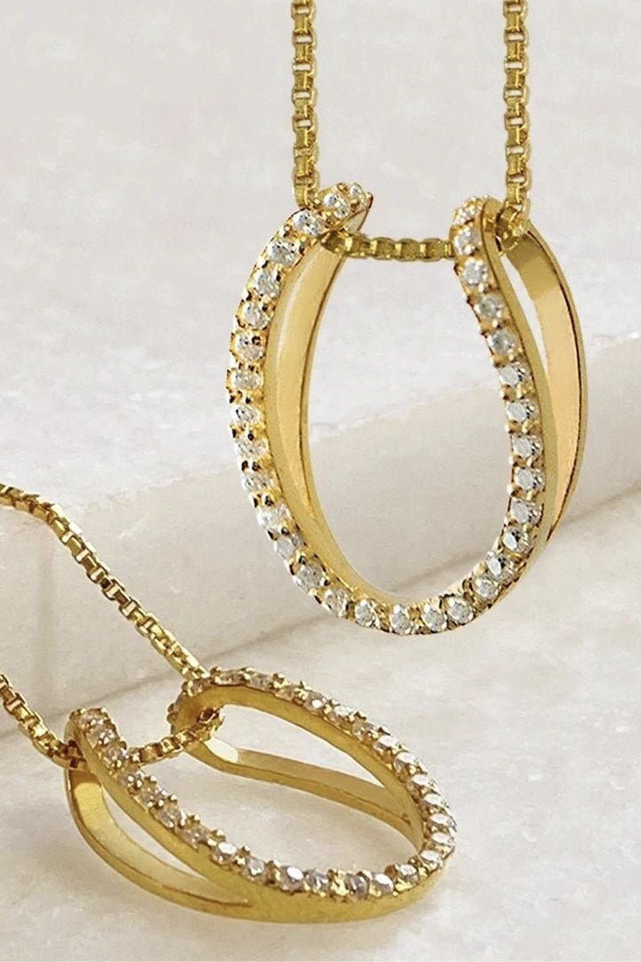 Two Levade Horseshoe Necklace in Gold Vermeil , one laying and one hanging showing the pendants