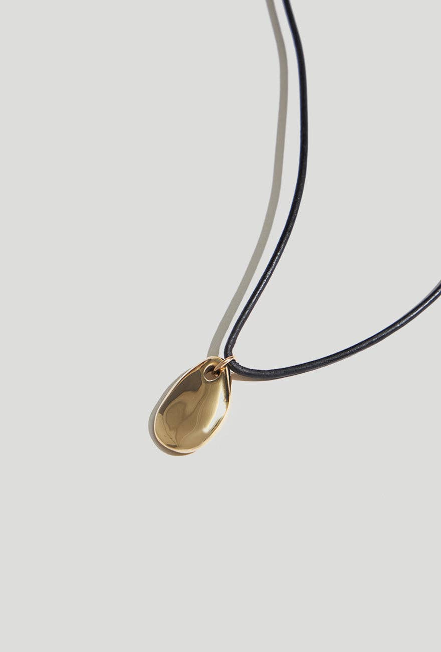 Louisa Gold Pebble Pendant Cork Necklace on a light gray background