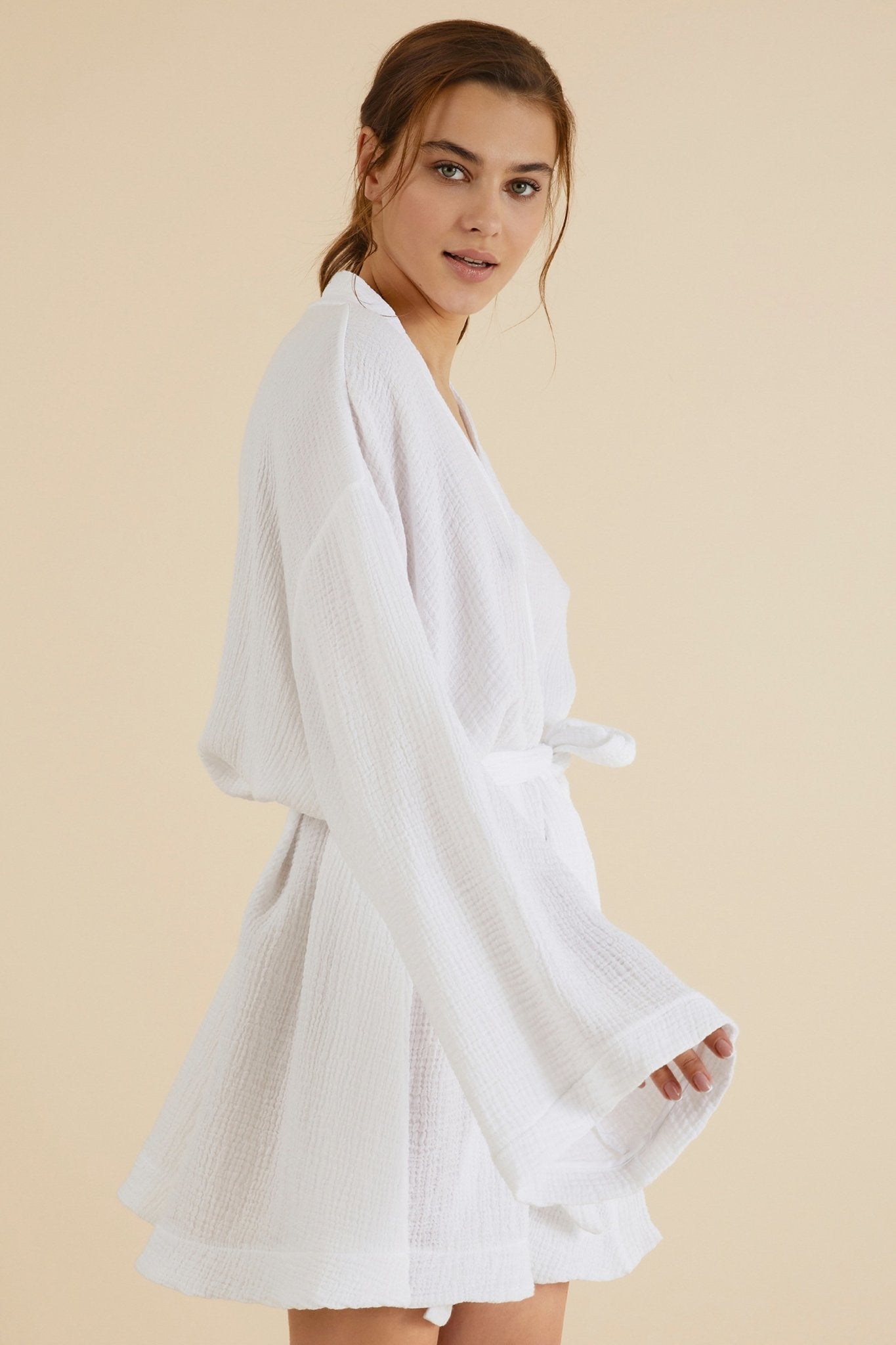 Side view of Luxe Luna Kimono Wrap on a model in front of a natural-hued background with light. She is presenting her right side showing the kimono long sleeve and belted back.