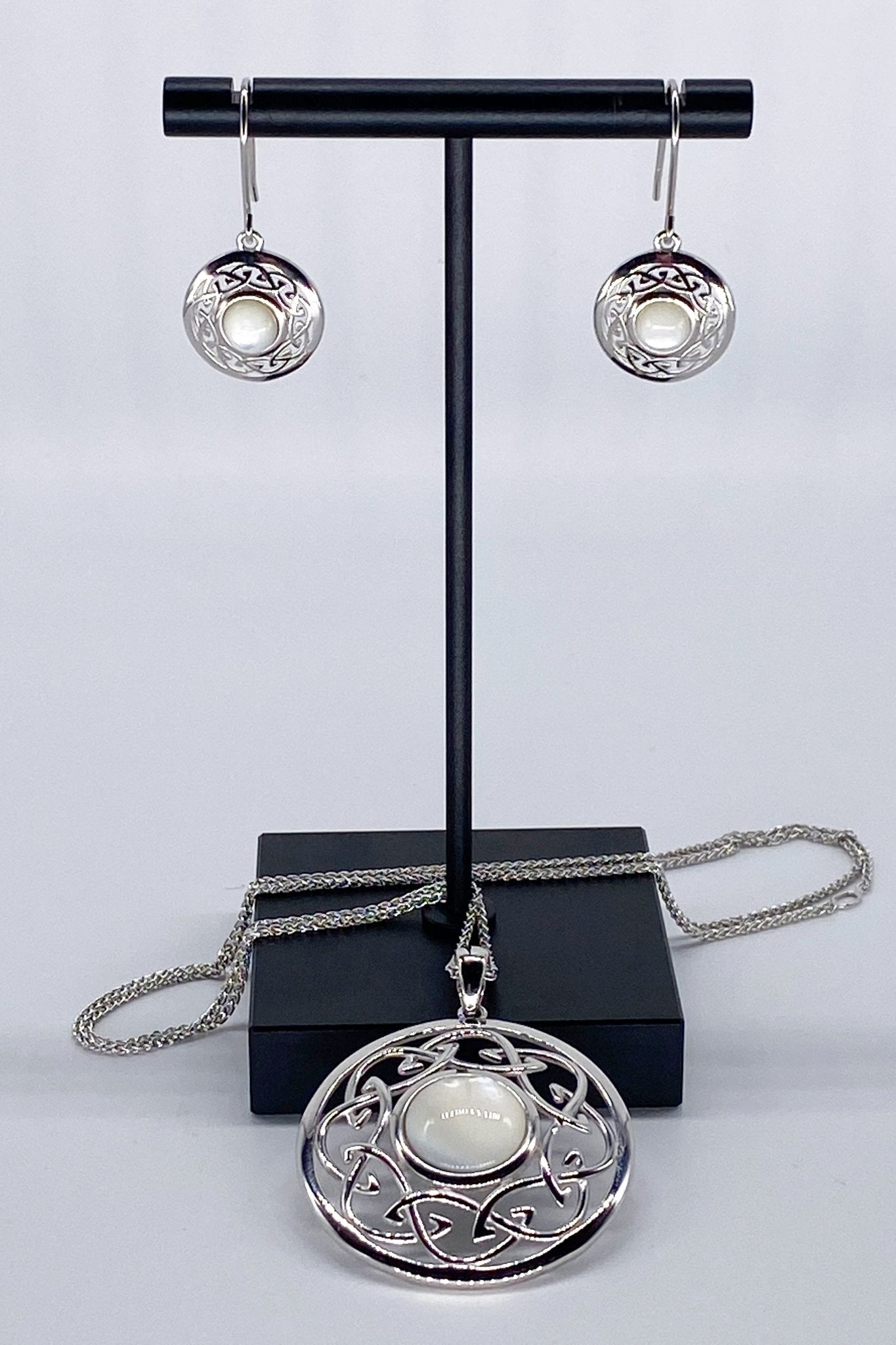 Mother of Pearl Trinity Silver Swirl Earrings with matching necklace on jewelry stand