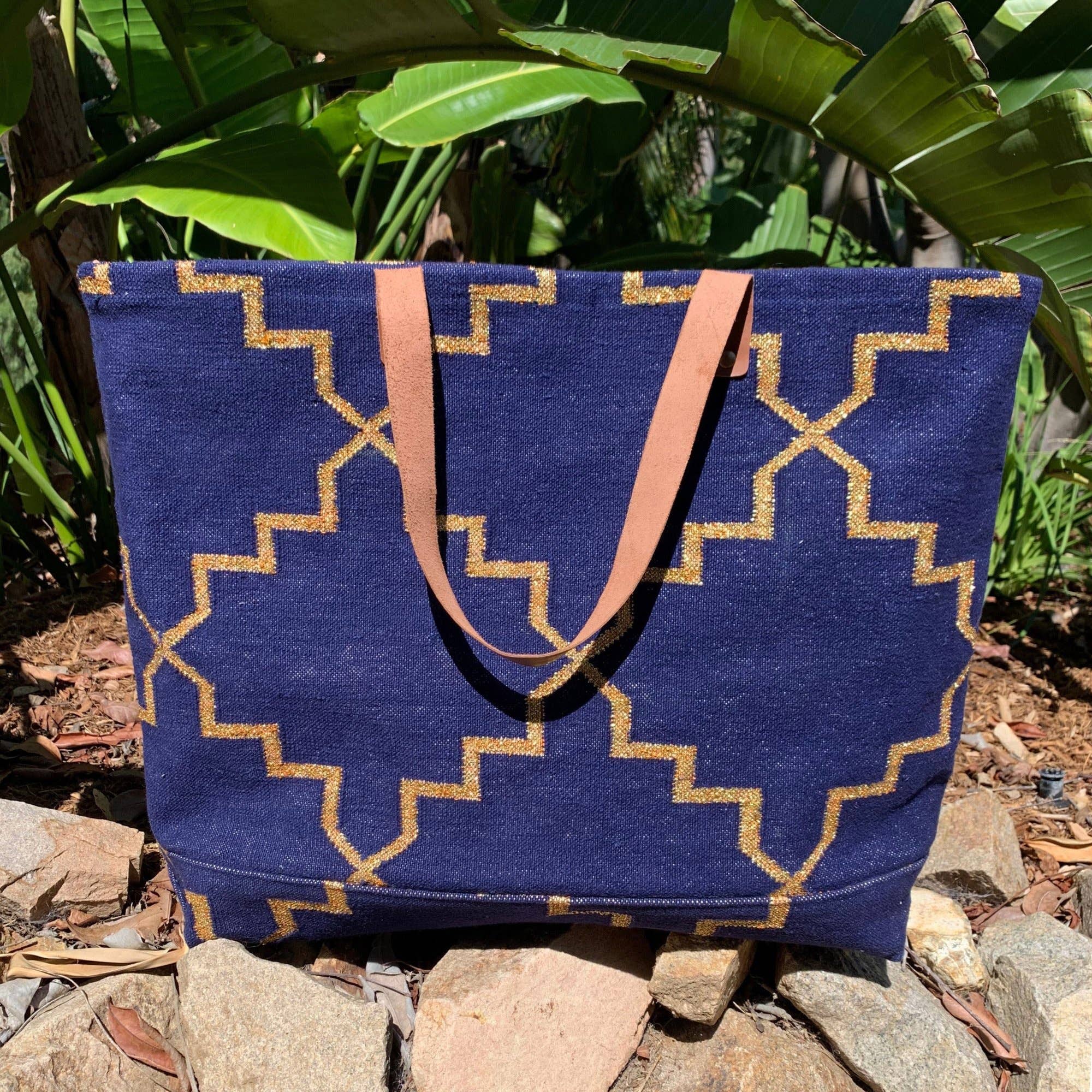 Npa Get Away Tote in navy with gold accents sitting in a cobble stone wall