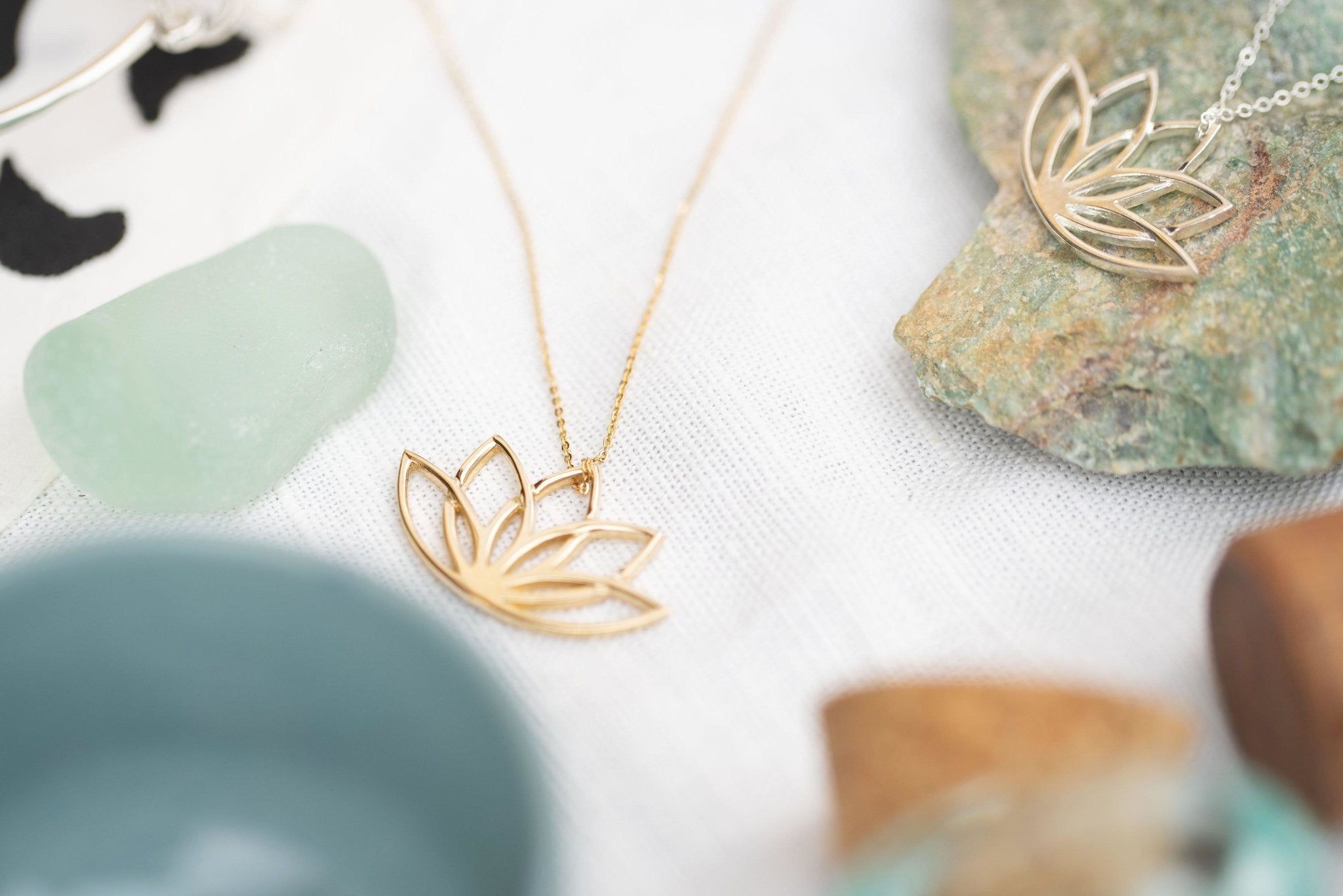 Irish New Beginnings Gold Necklace laying on a white table surrounded by pottery - L'Atelier Global