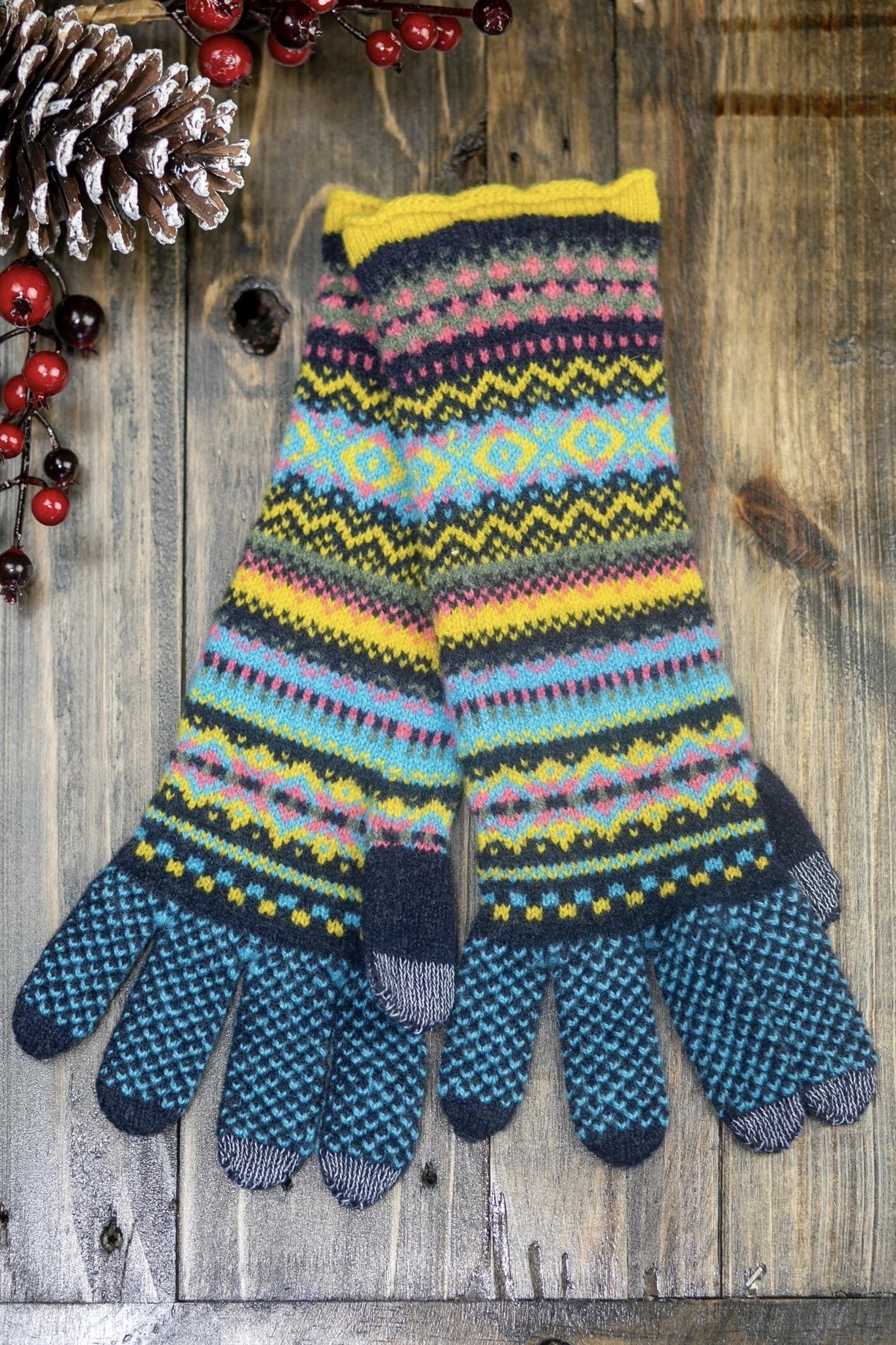 Northern Isles Merino Wool Glove in Blue on wood background with snowy pinecone in top left - L'Atelier Global