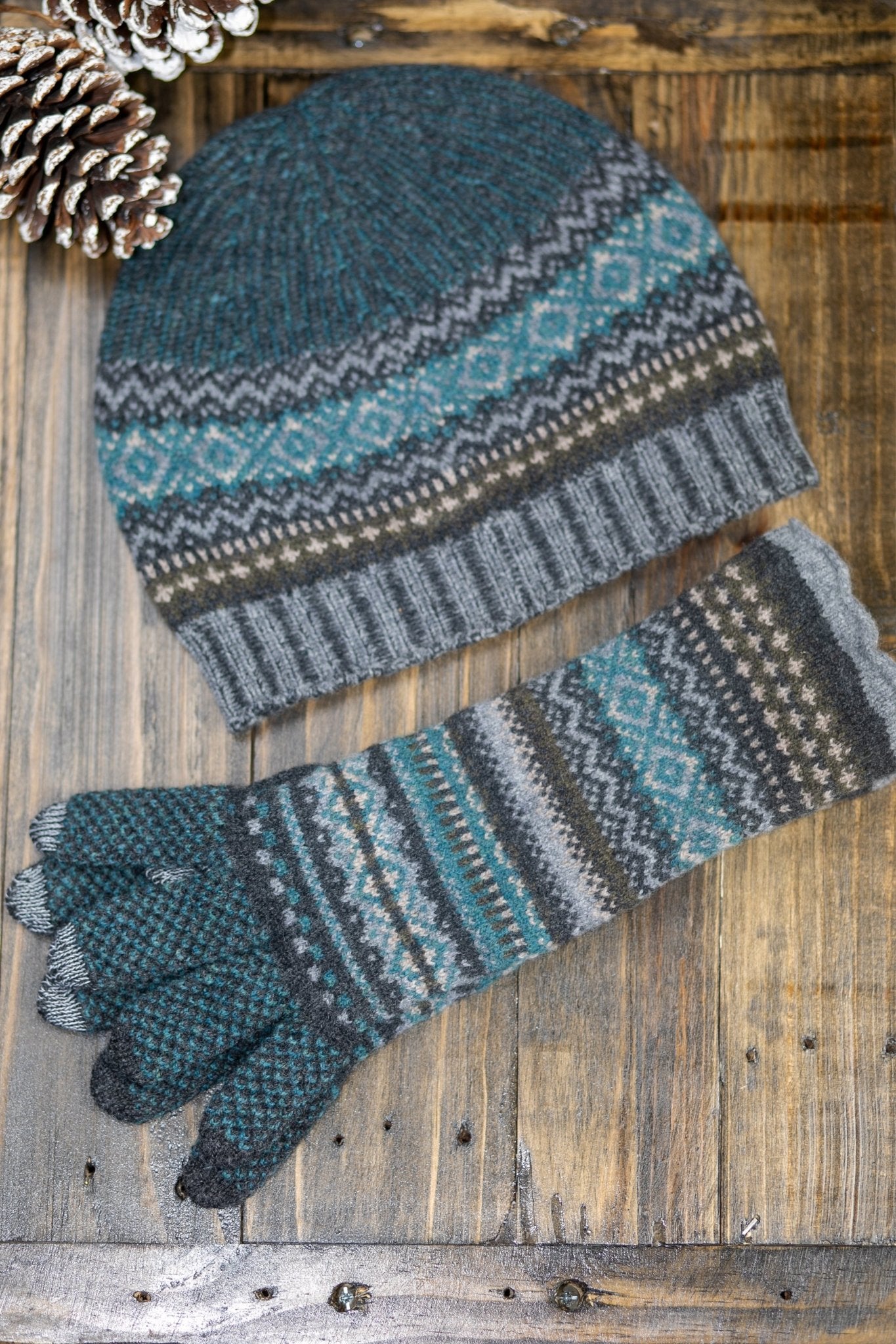 Northern Isles Merino Wool Beanie and Gloves in Gray on a wood background with snowy pinecone in top left - L'Atelier Global