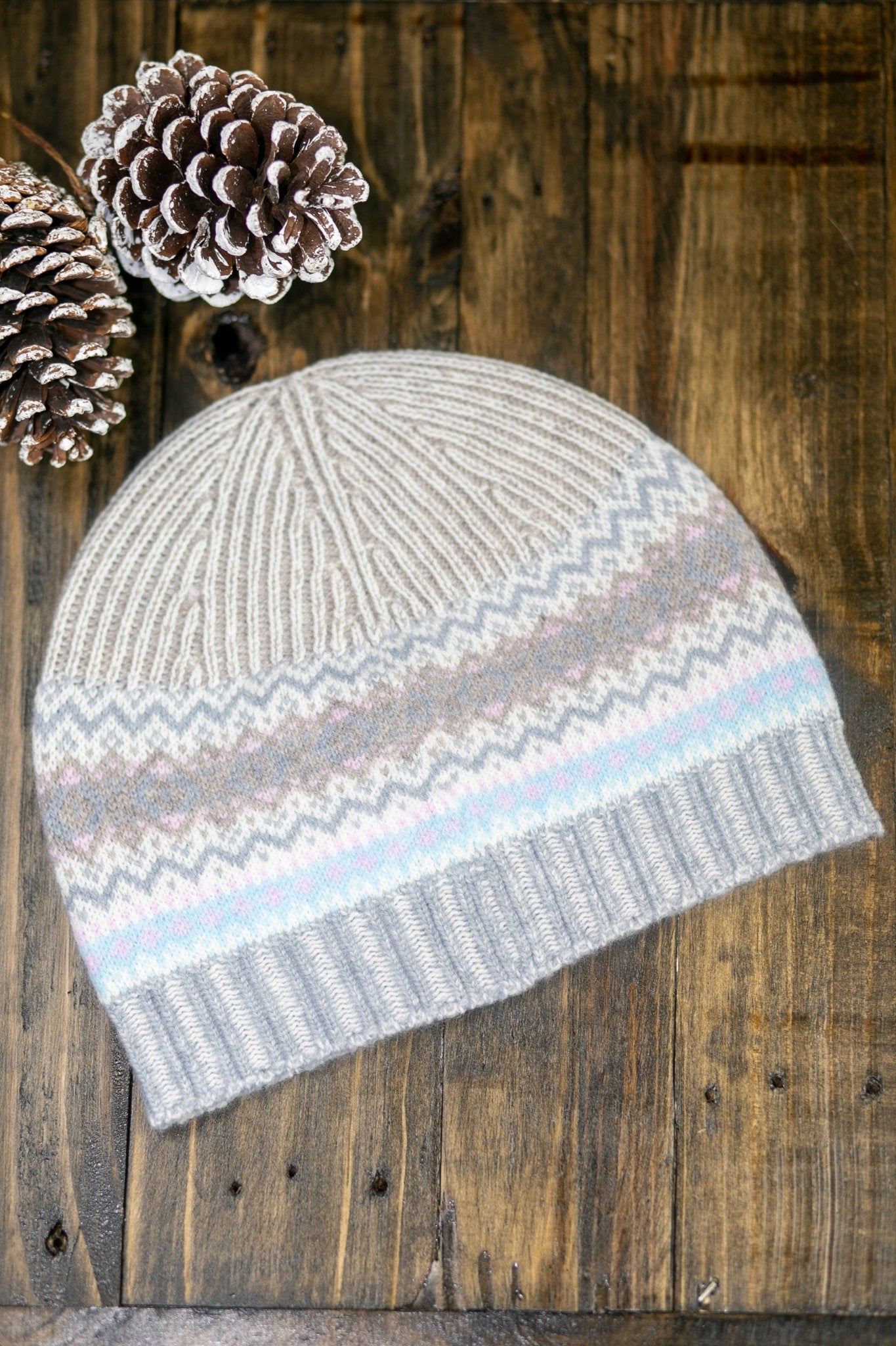 Northern Isles Merino Wool Beanie in Mist laying on a wood background with snowy pinecone in top left - L'Atelier Global