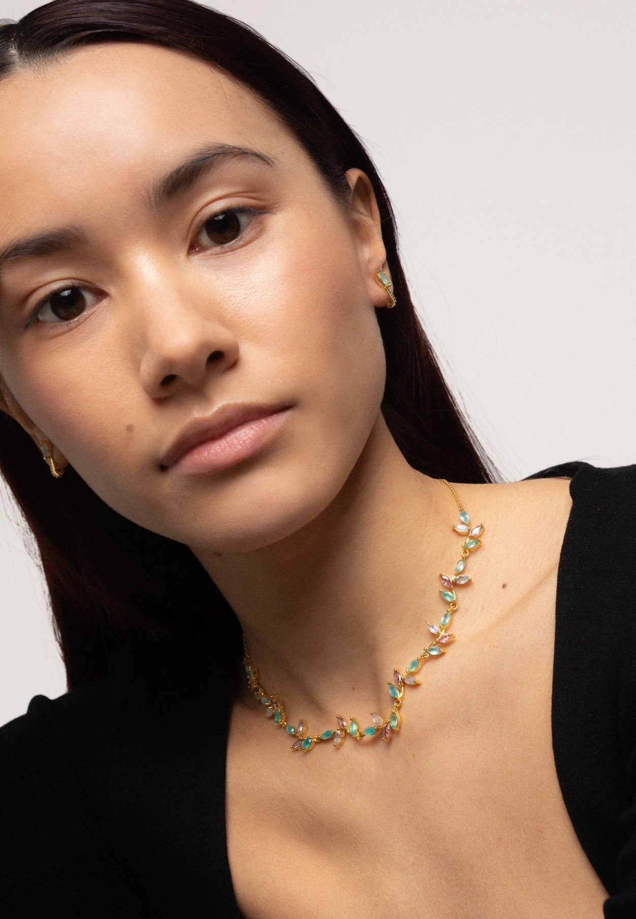 A female model wearing a black opened neck cardigan is wearing the Padma Lotus Flower Spanish Choker Necklace - L'Atelier Global