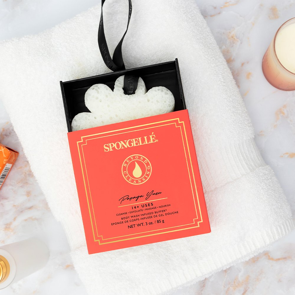 Papaya Yuzu Flower Spa Body Buffer in orange shipping box on a white towel.