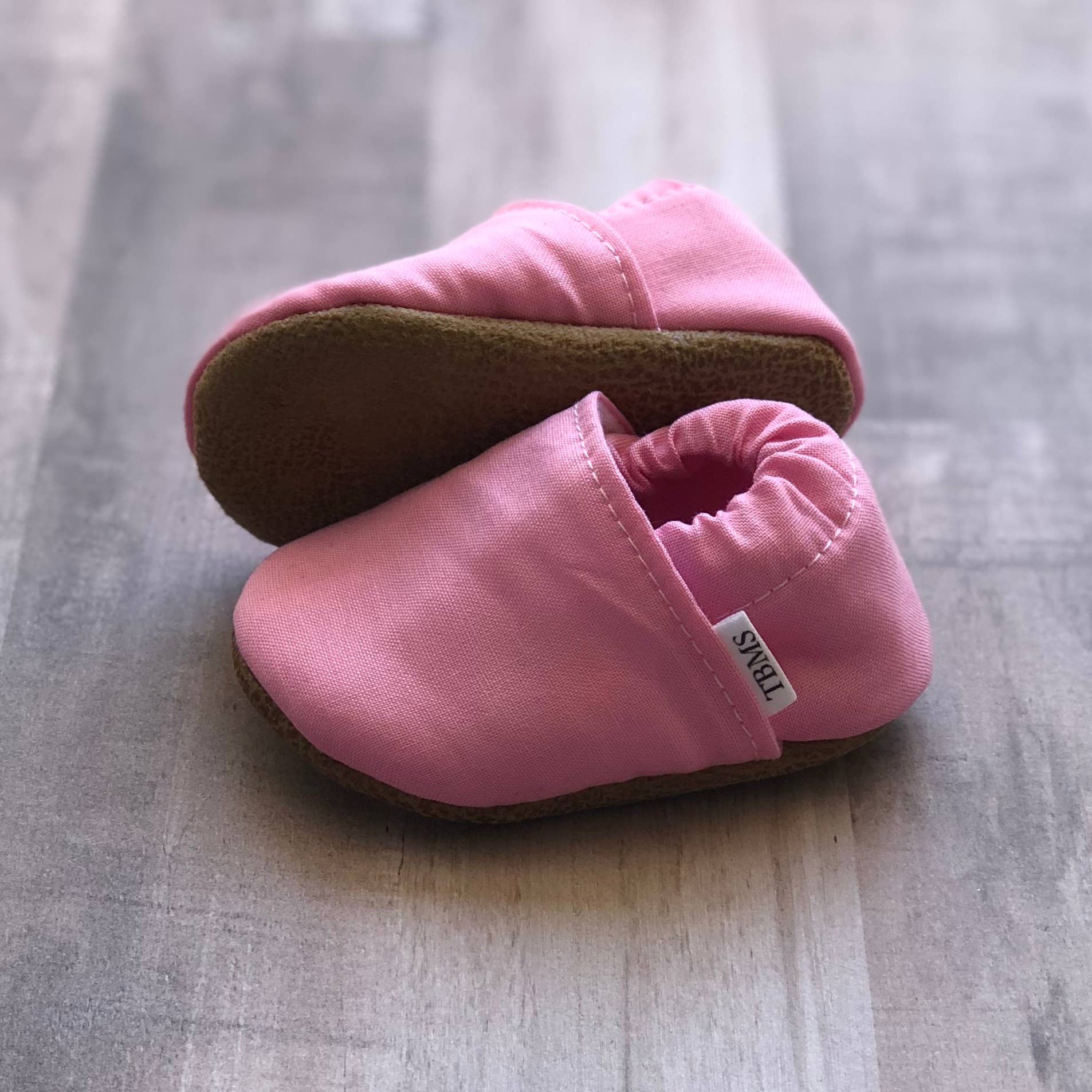 Pink Cotton Canvas Moccasins on a soft ash hued wood table