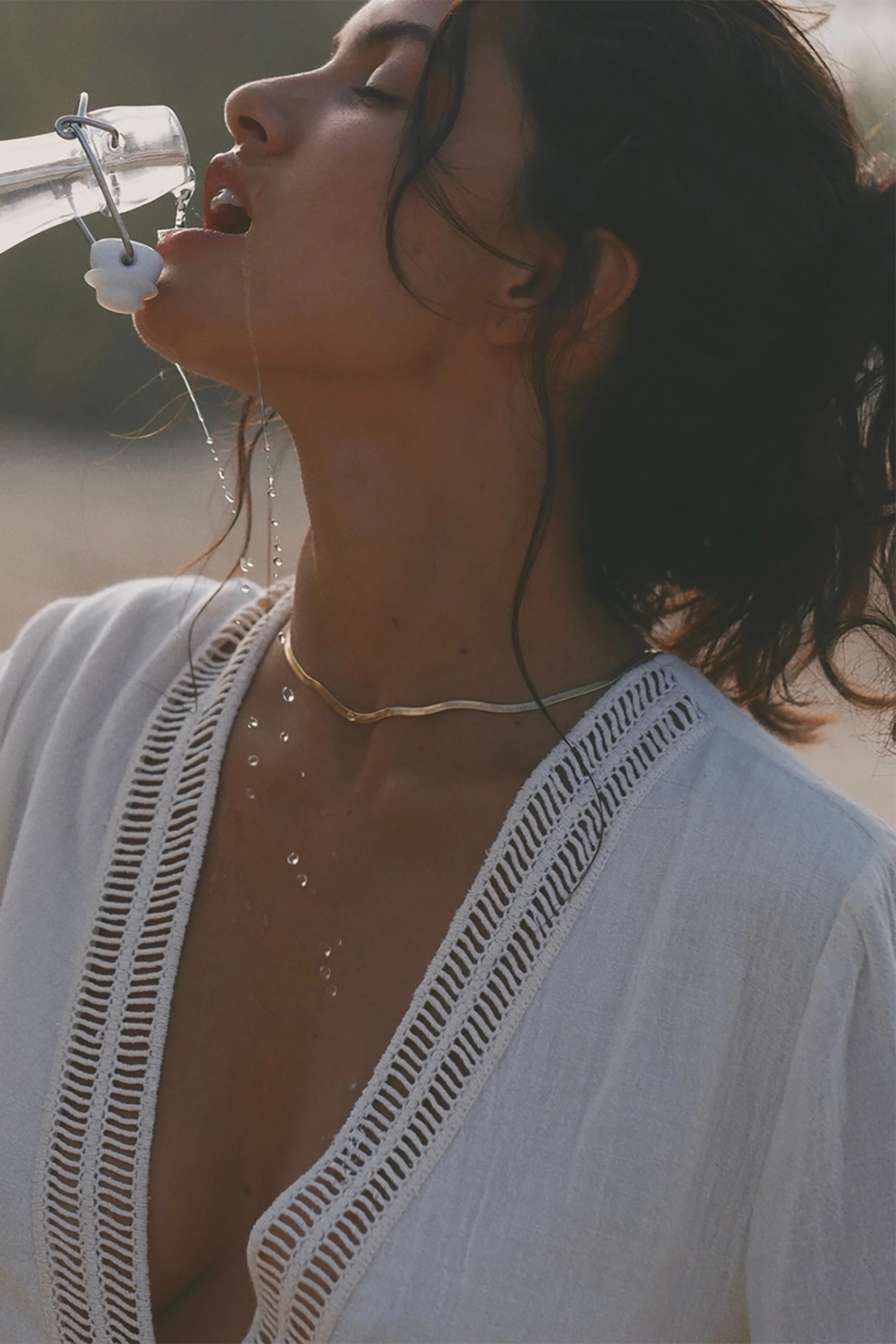 Close view of the model drinking and the lace v-neck of the Positano Turkish Cotton Cover Up Dress with Lace in Natural.