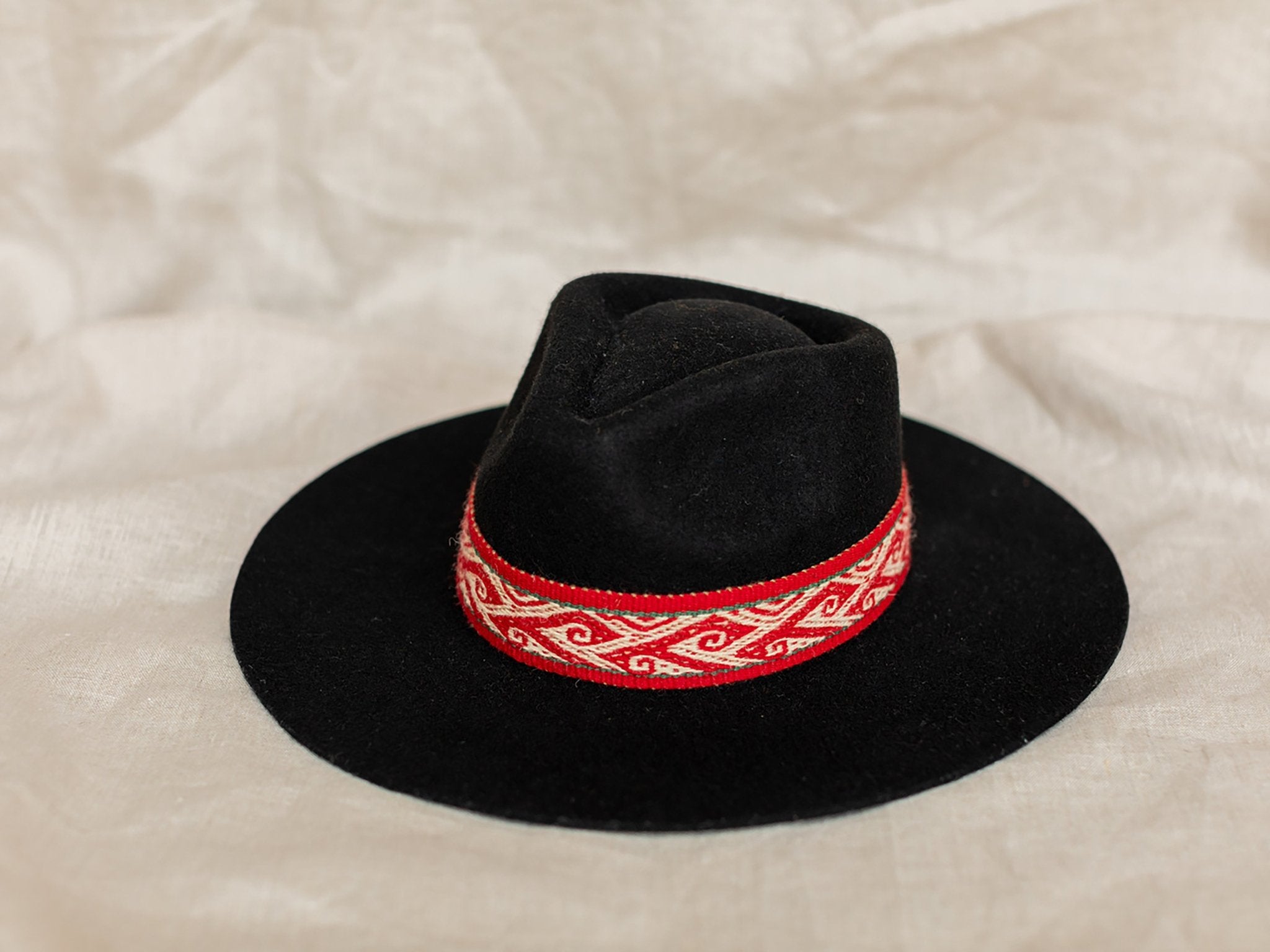 Puma Alpaca Hat in black with red removable intention band on a tan background- L'Atelier Global