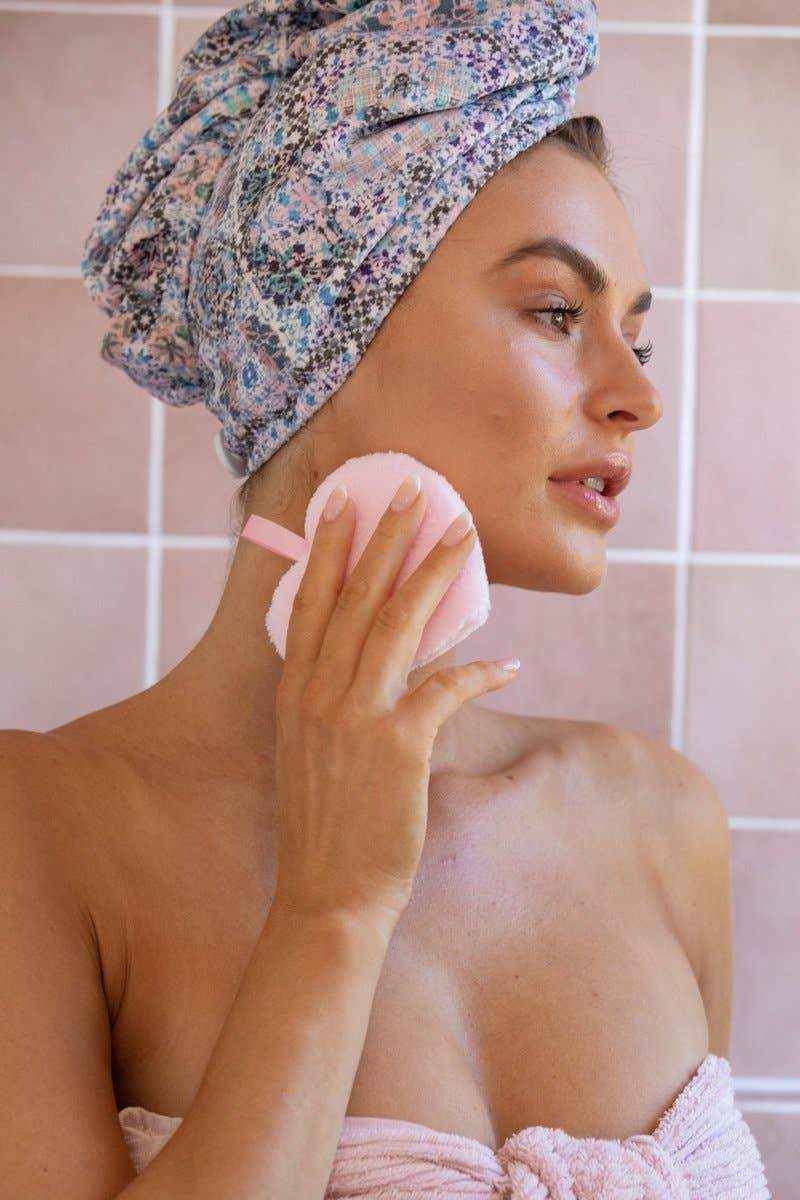 A woman is holding the Pure Hearts Makeup Removal Pad by her chin