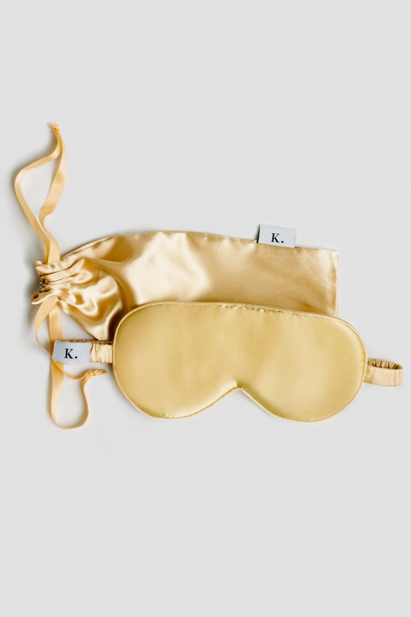 Pure Mulberry Gold Silk Sleep Mask in yellow with its yellow silk carry case laying on a white background - L'Atelier Global