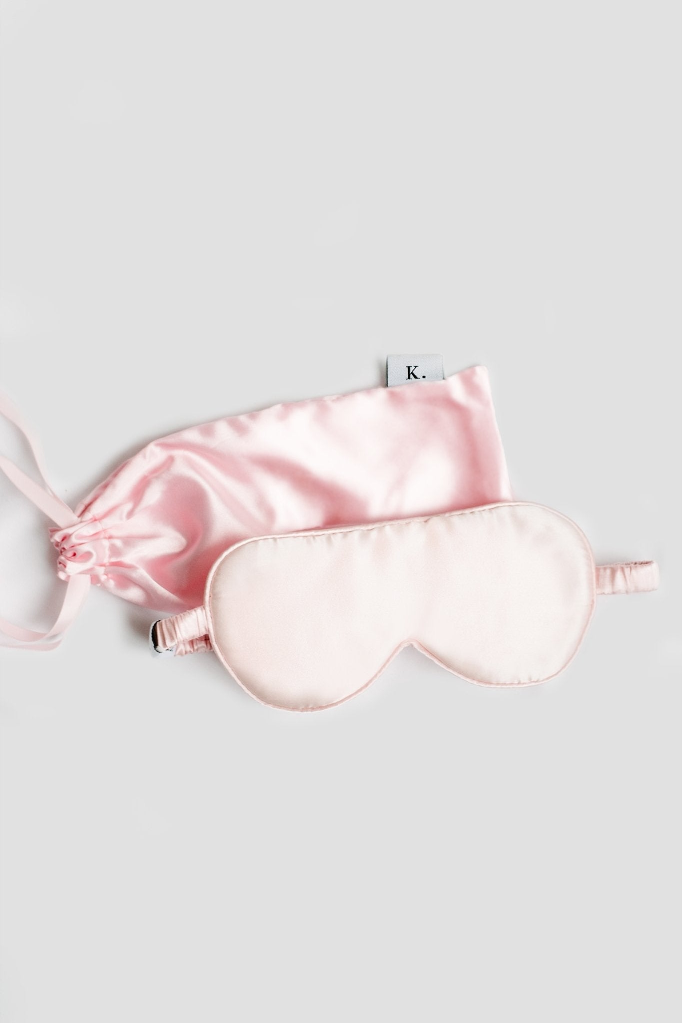 Pure Mulberry Gold Silk Sleep Mask in pink with its pink silk carry case laying on a white background - L'Atelier Global