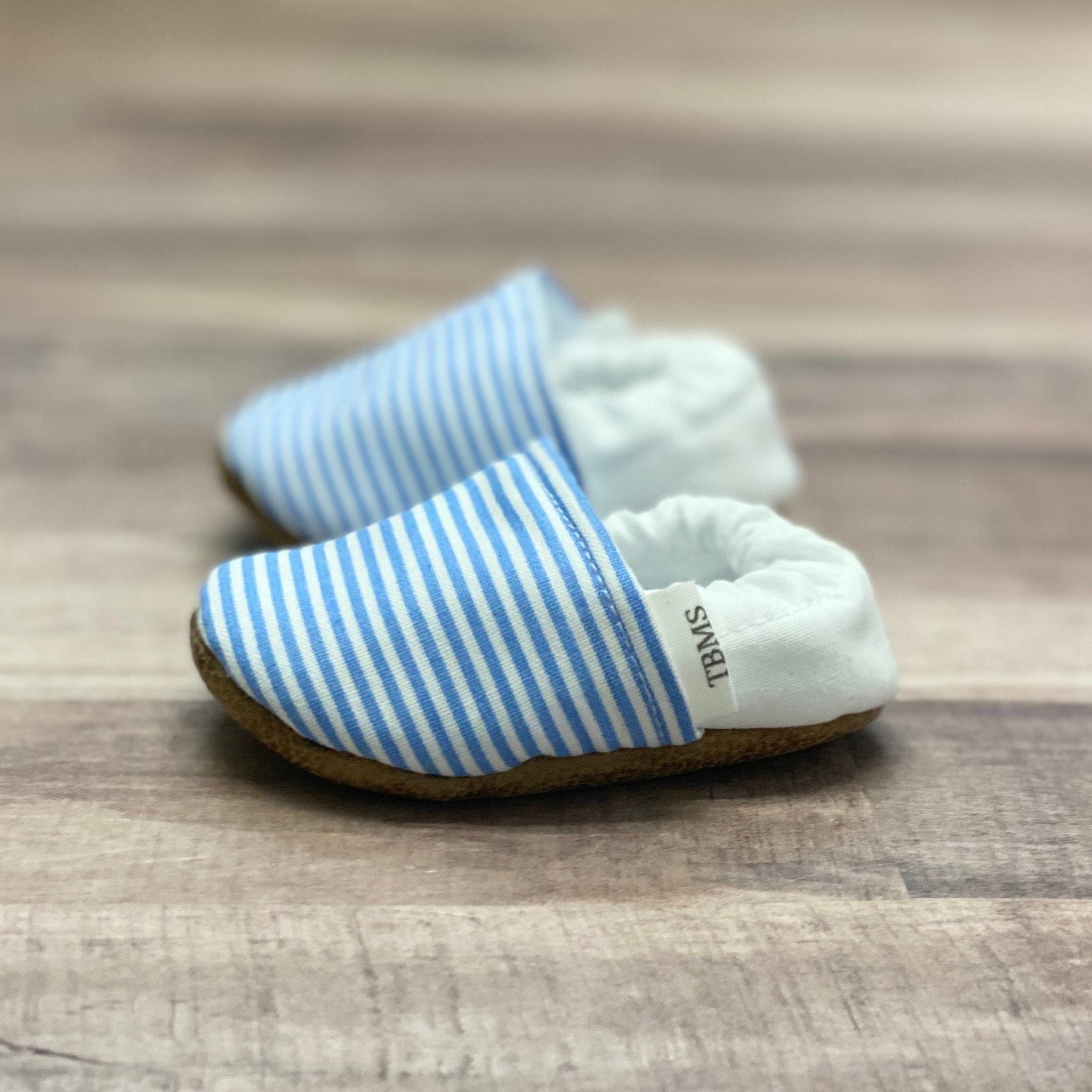 Side view Sailor Striped Cotton Canvas Moccasins on a soft ash hued wood table