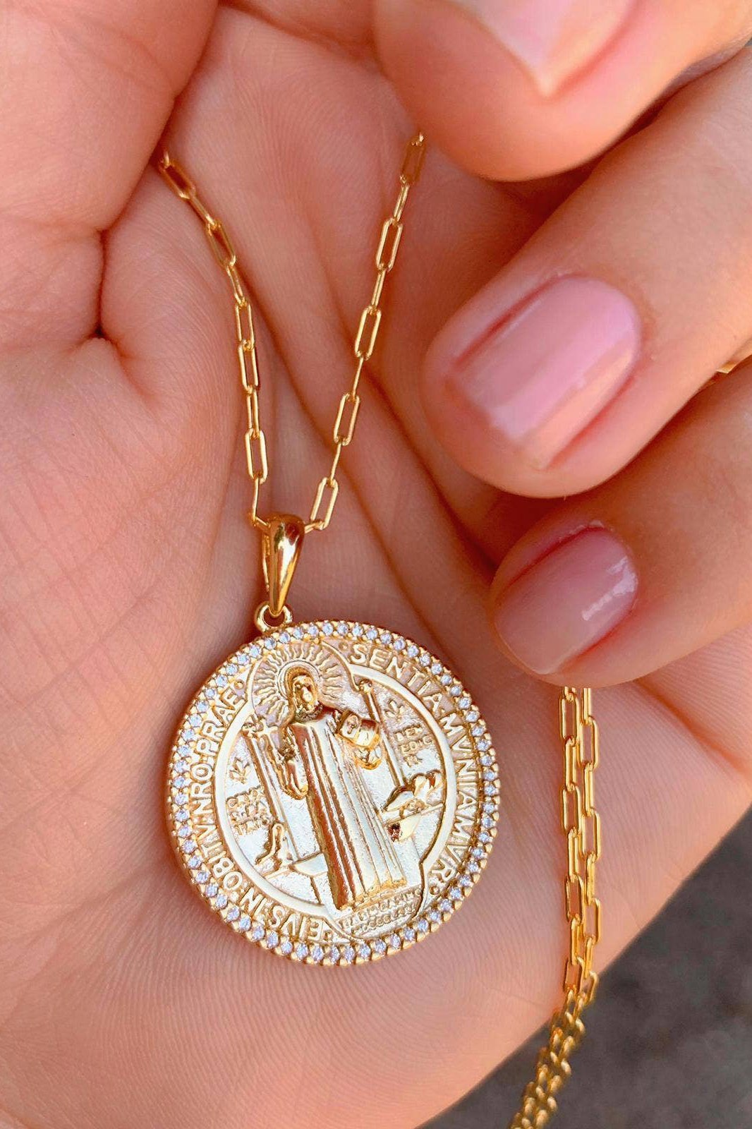 A model is holding the Saint Benedict Coin Necklace in her palm - L'Atelier Global