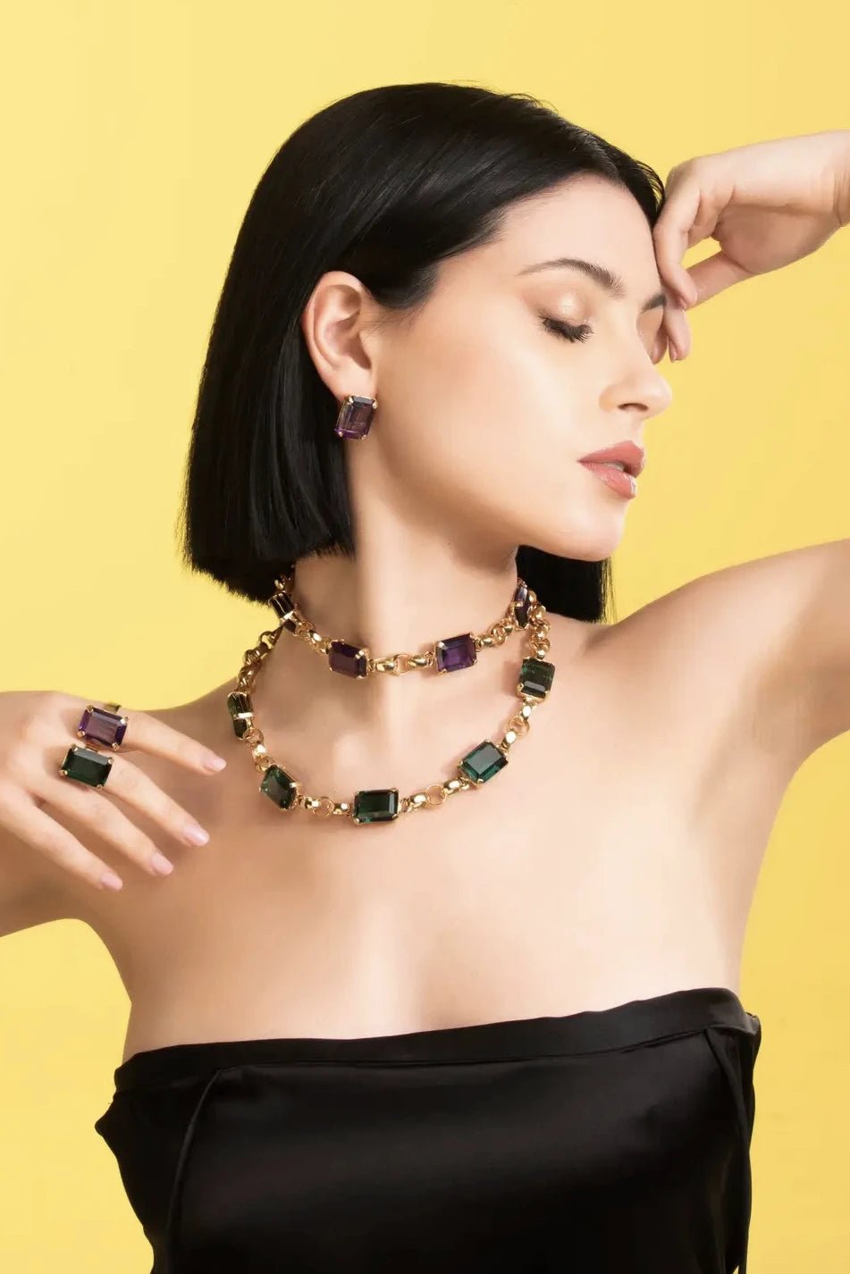 Sassari Amethyst Golden Adjustable Ring on a model wearing a black strapless dress in front of a yellow background