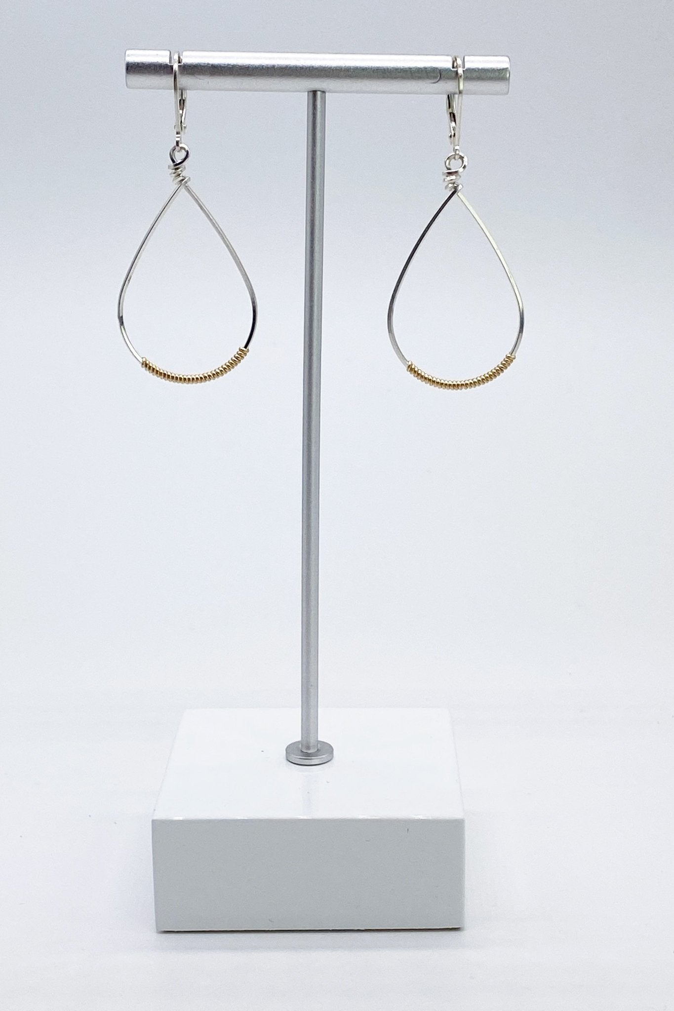 Signature Silver/wrapped Gold Small Oval Wrapped Hoops on a silver jewelry stand