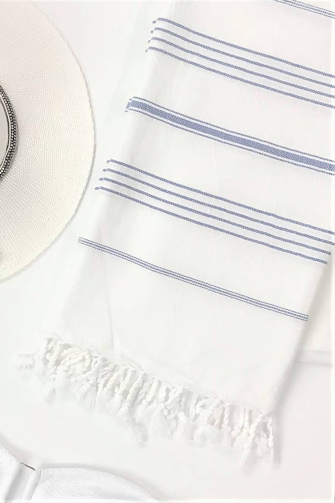 Signature Turkish Cotton Striped Towel in Blue on a white background with a straw sun hat