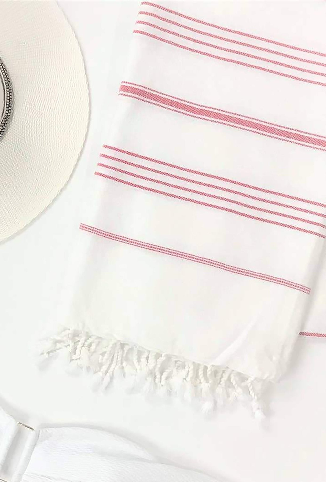 Signature Turkish Cotton Striped Towel in Pink on a white background with a straw sun hat