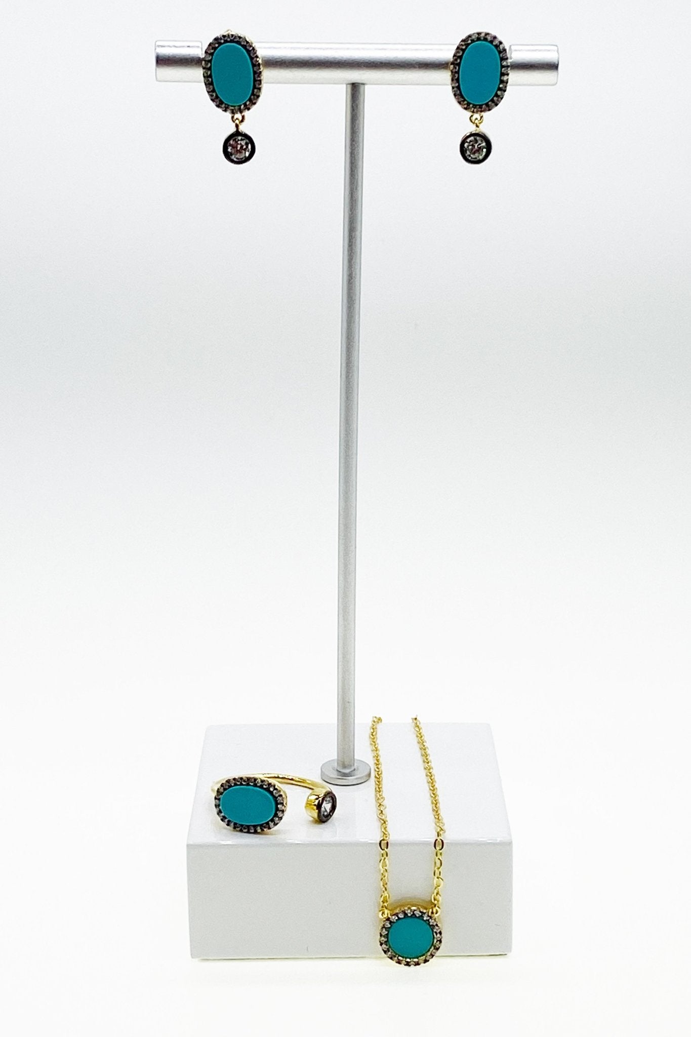Signature Turquoise Pendant Gold Necklace and matching earrings on silver jewelry stand white marble base - L'Atelier Global