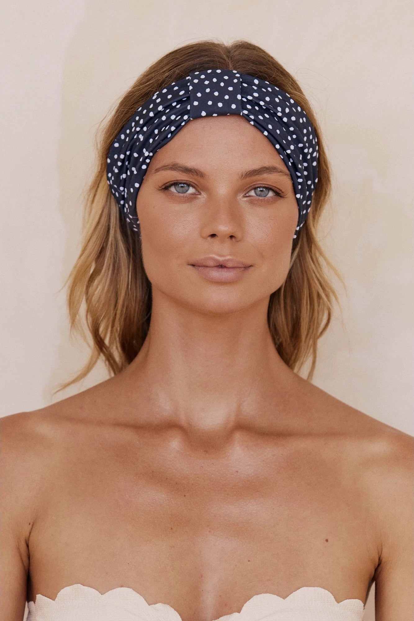 A woman is wearing a Navy and White Polka Dot Headband with a white strapless top