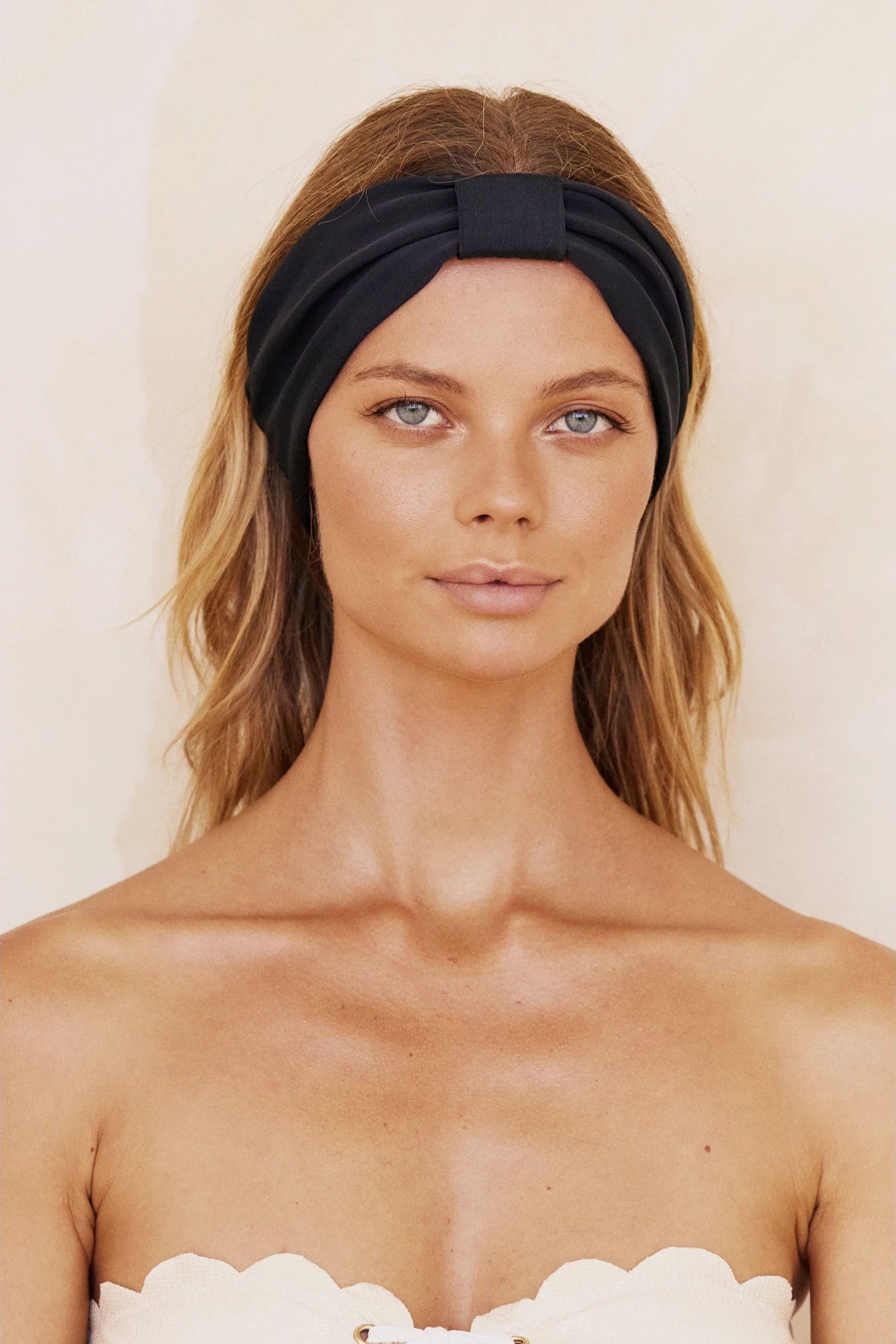 A model wearing a black headband that is designed to secure hair during face treatments or casually.
