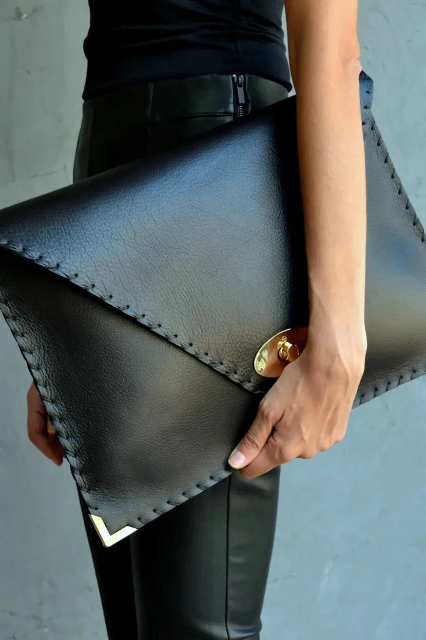 Symmetria Executive Leather Clutch in black held by a woman