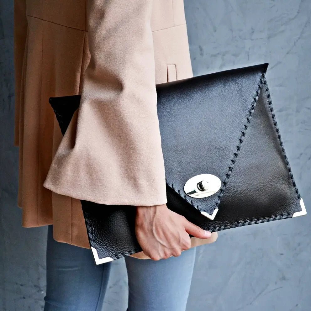 Symmetria Executive Leather Clutch in black held by a woman in a pink blazer