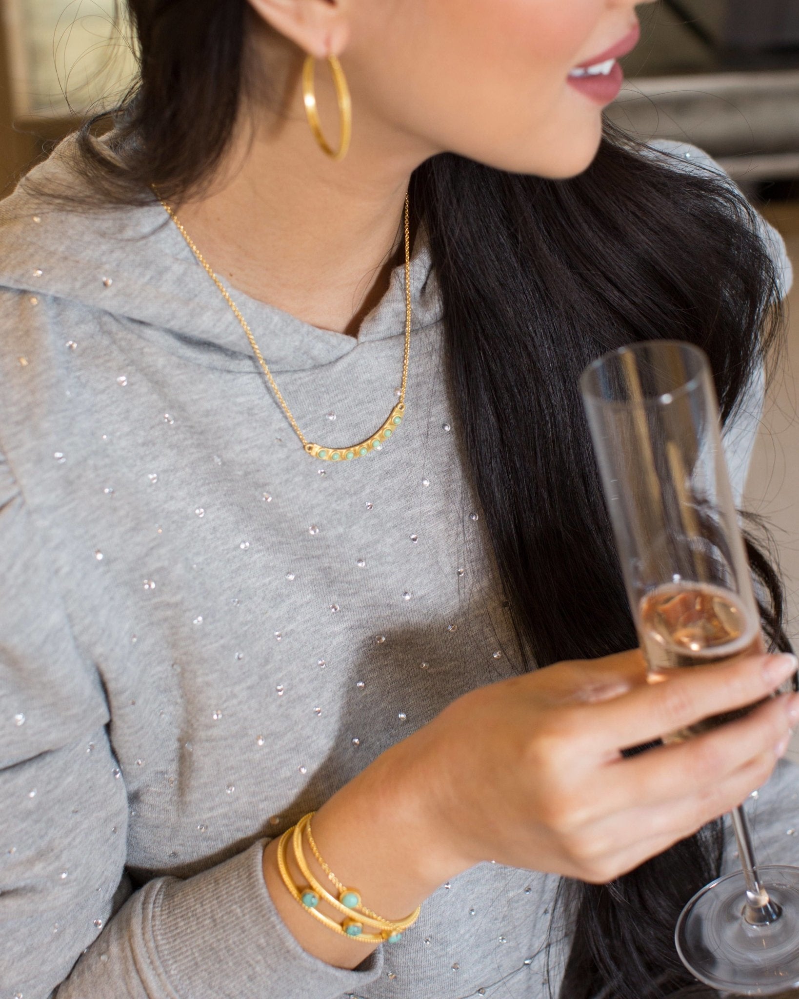 Turquoise Studded Bracelet on model's left wrist as she holds a champagne flute - L'Atelier Global