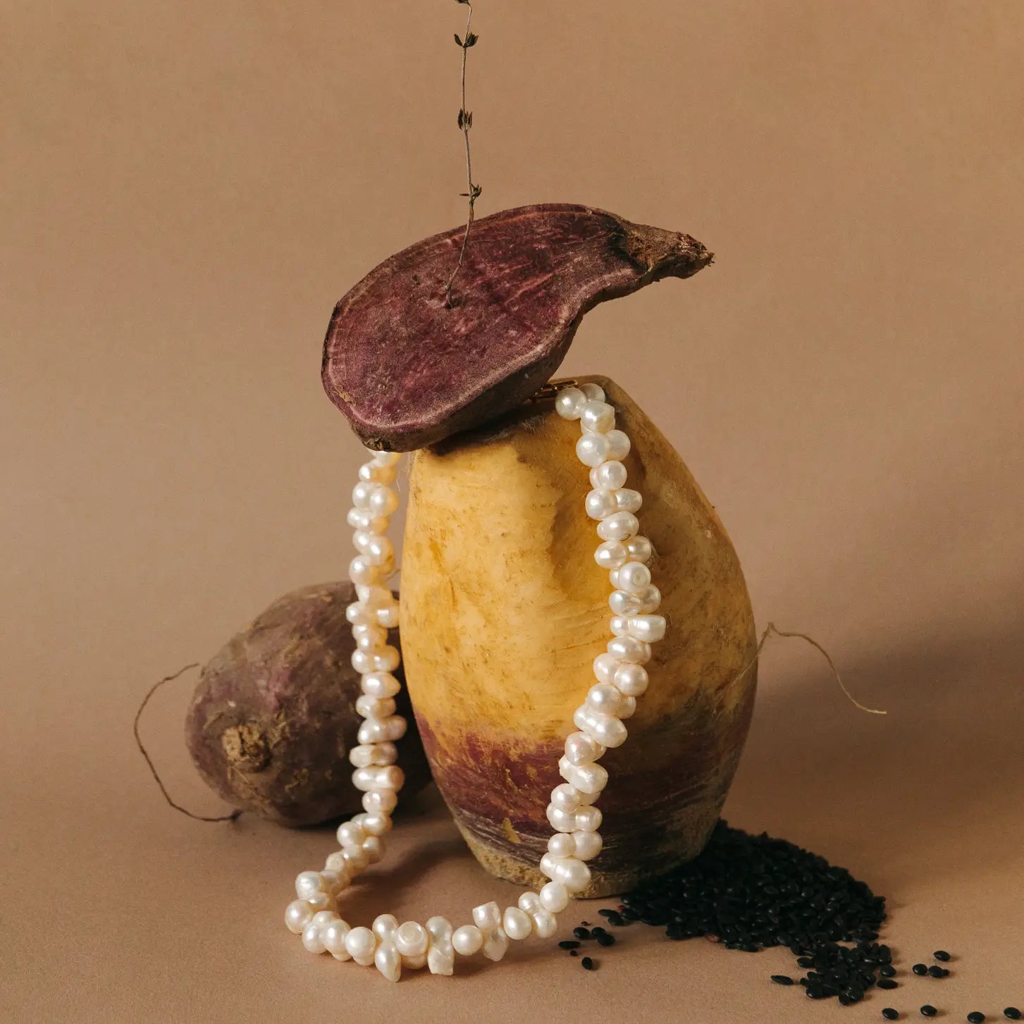 Decoraive photo of the Valence Cultured Pearl necklace on a root vegetable and a fig