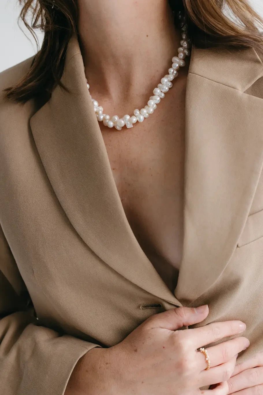 A model wearing the Valence Cultured Pearl necklace on a beige suit