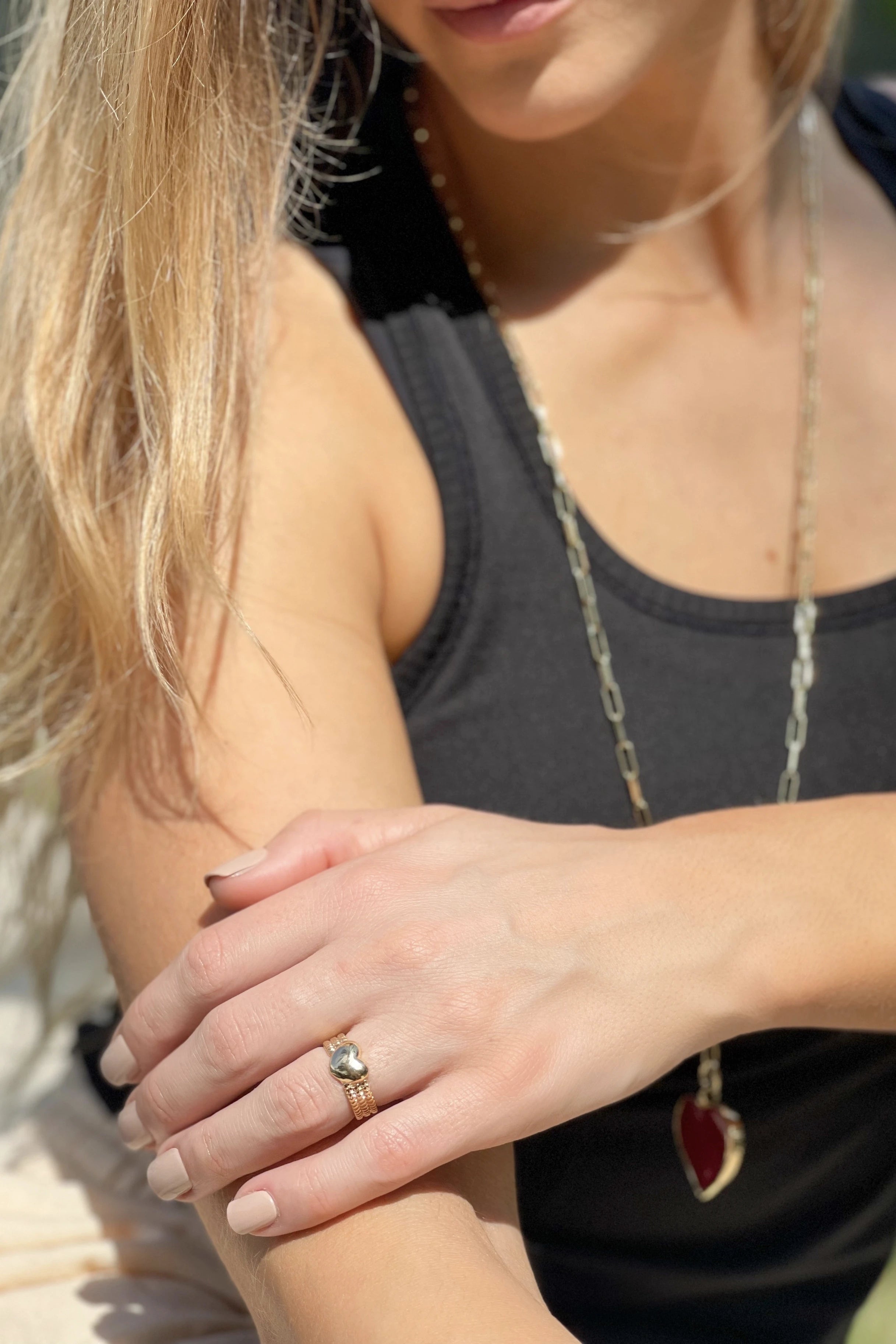 Verona Gratitude Heart Adjustable Ring on a model's left hand crossed in front her body, laying on her right arm - L'Atelier Global