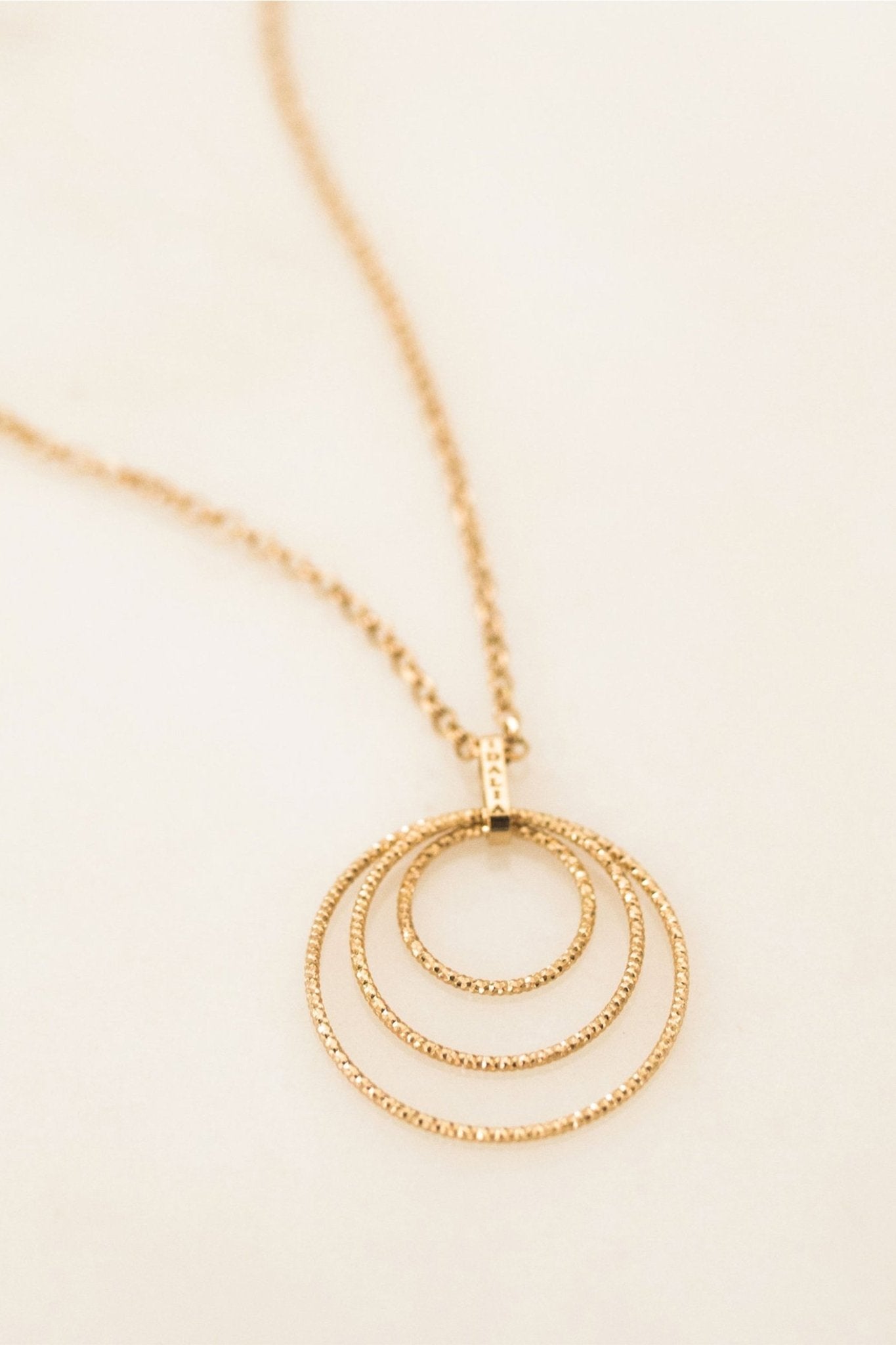 Vincenze Circle Trio Necklace in gold on a beige background - L'Atelier Global