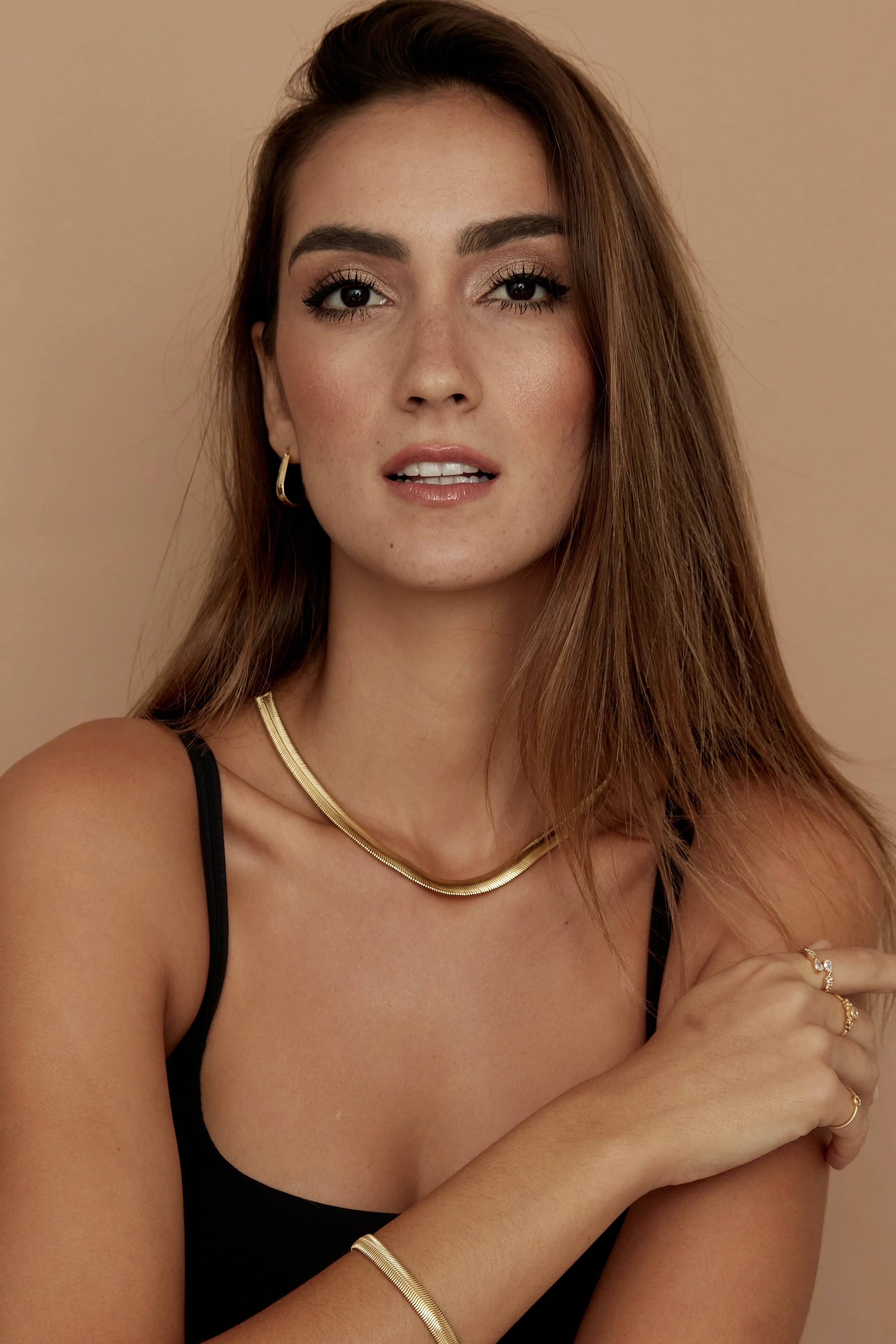Vitoria Golden Snake Chain on a model wearing a black strapless tank that complements her gold jewelry - L'Atelier Global