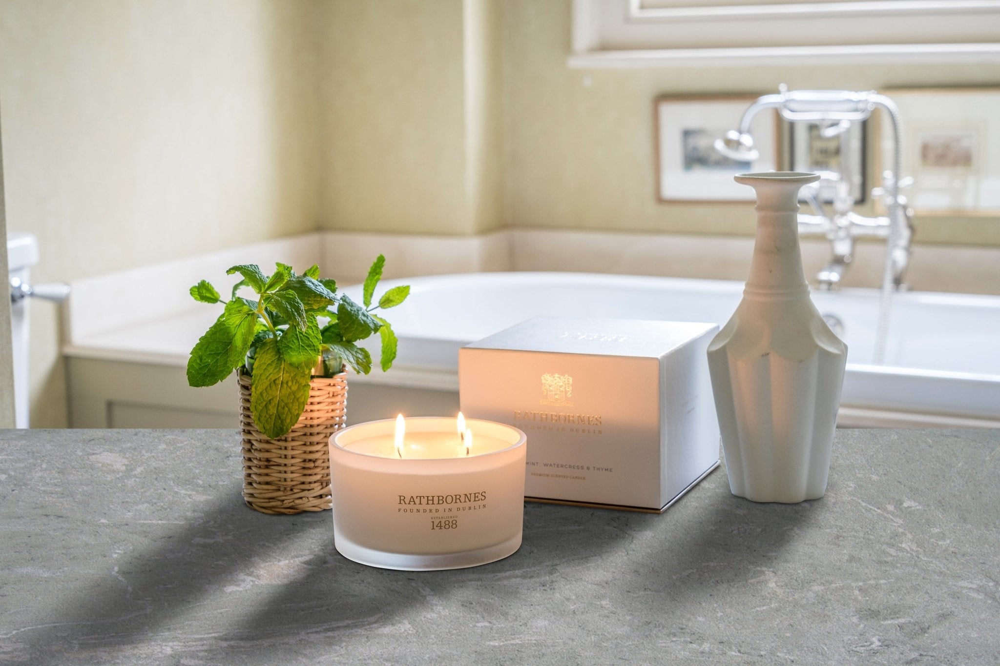 Wild Mint, Watercress and Thyme Luxury Beeswax Candle lit on a bathroom counter
