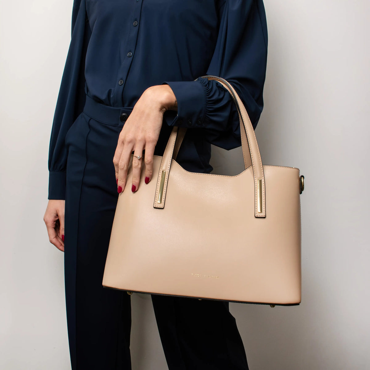 Person holding a Olimpia beige handbag against a plain background