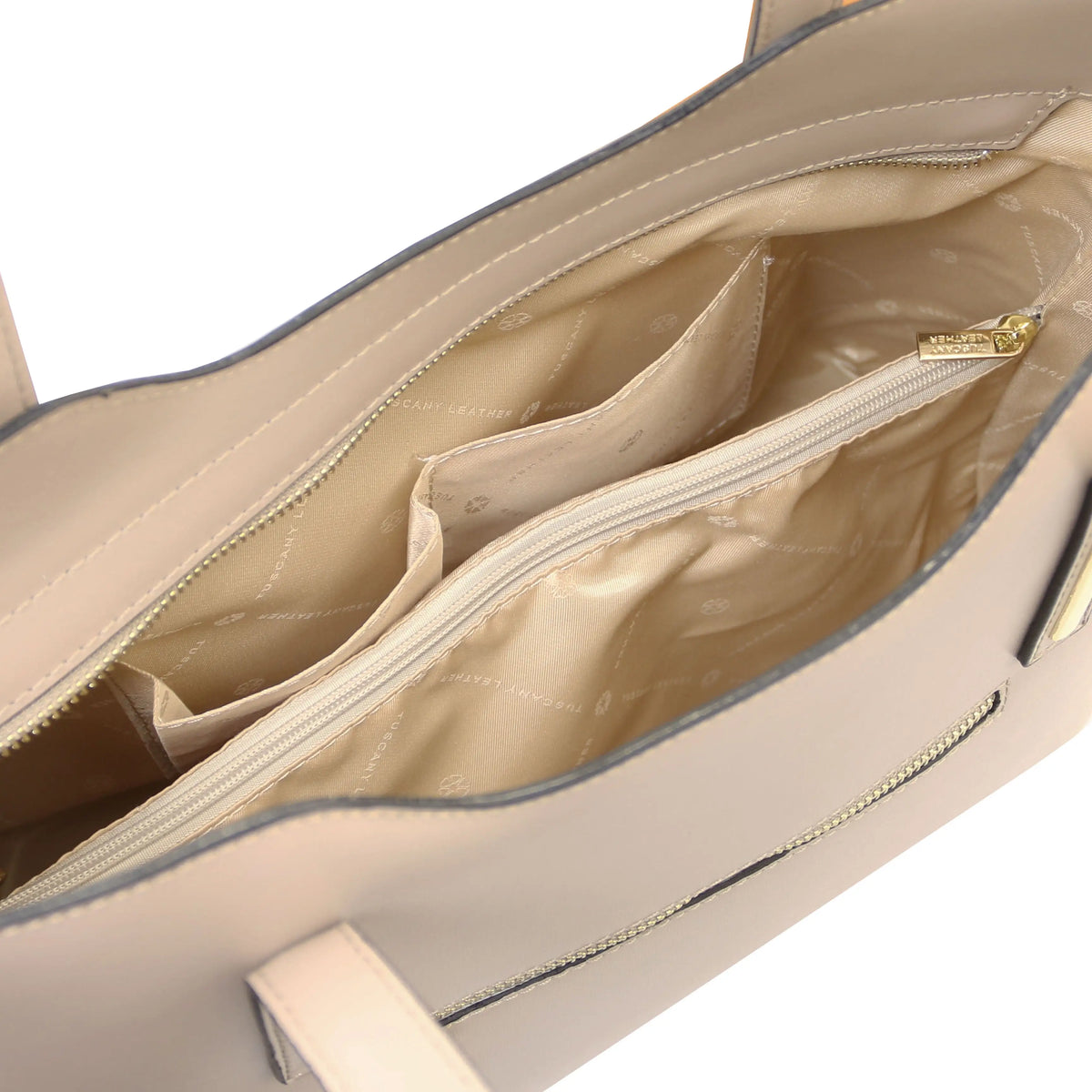 Close-up of the interior of a structured handbag in light taupe leather, showing a quilted cream lining with multiple zip compartments and gold-tone hardware.
