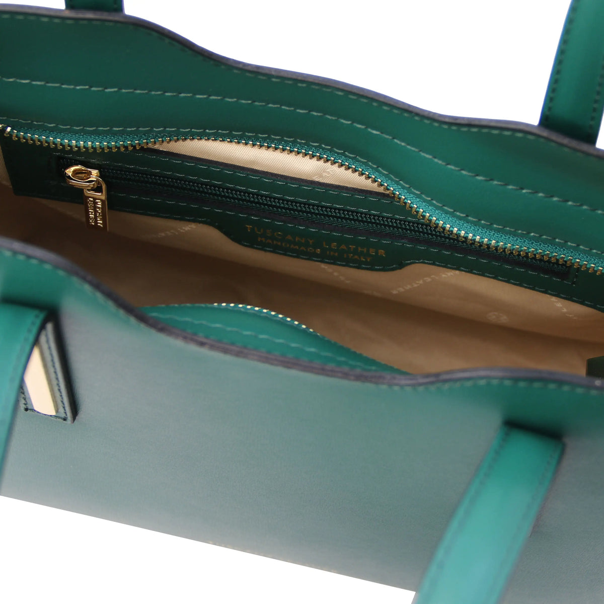 Interior view of a teal handbag with visible stitching, zippered pocket and beige lining. 