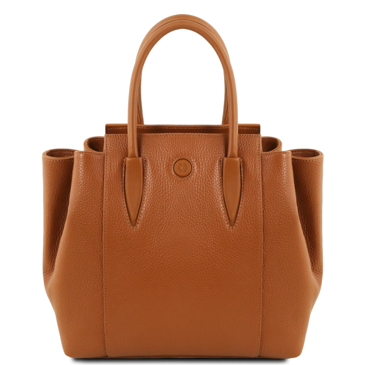 A structured cognac pebbled leather handbag with double top handles and a circular leather accent on the front, photographed against a solid white background.