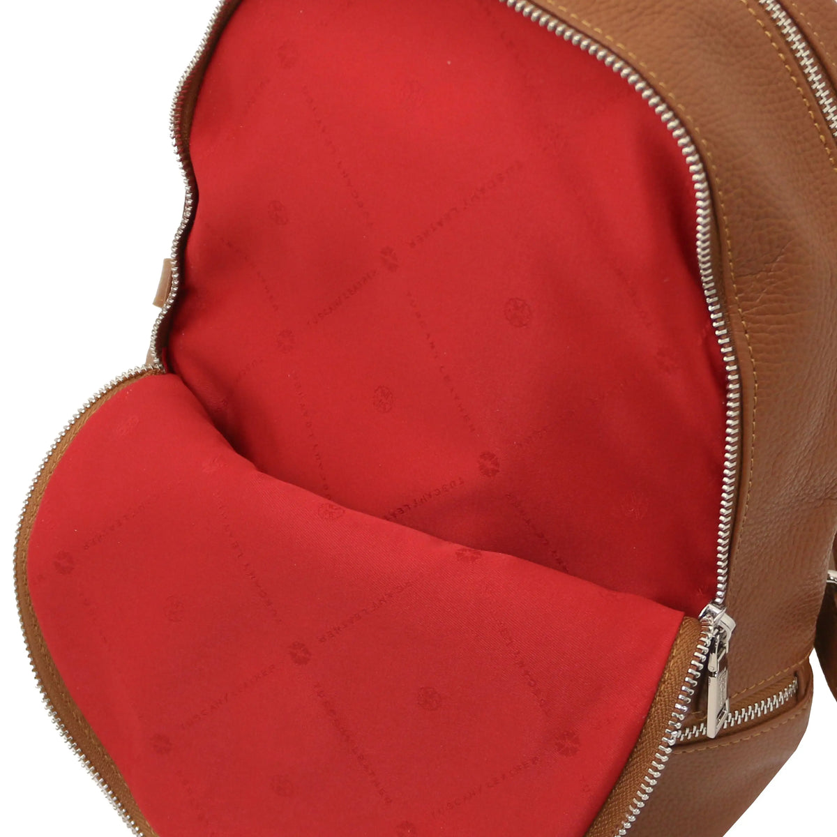 Close-up of a cognacleather backpack showing the red interior lining and silver zipper.