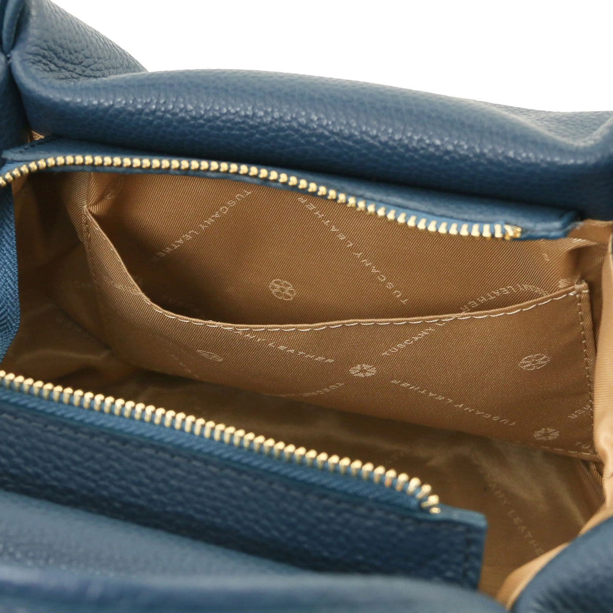 Close-up of a teal textured leather handbag showing the interior with a gold zipper and a tan lining printed with the brand name Tuscany Leather.