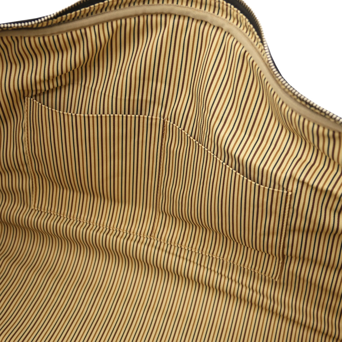 Close-up of a striped fabric interior with a zipper along the top edge and a stitched pocket on a beige and black striped background.