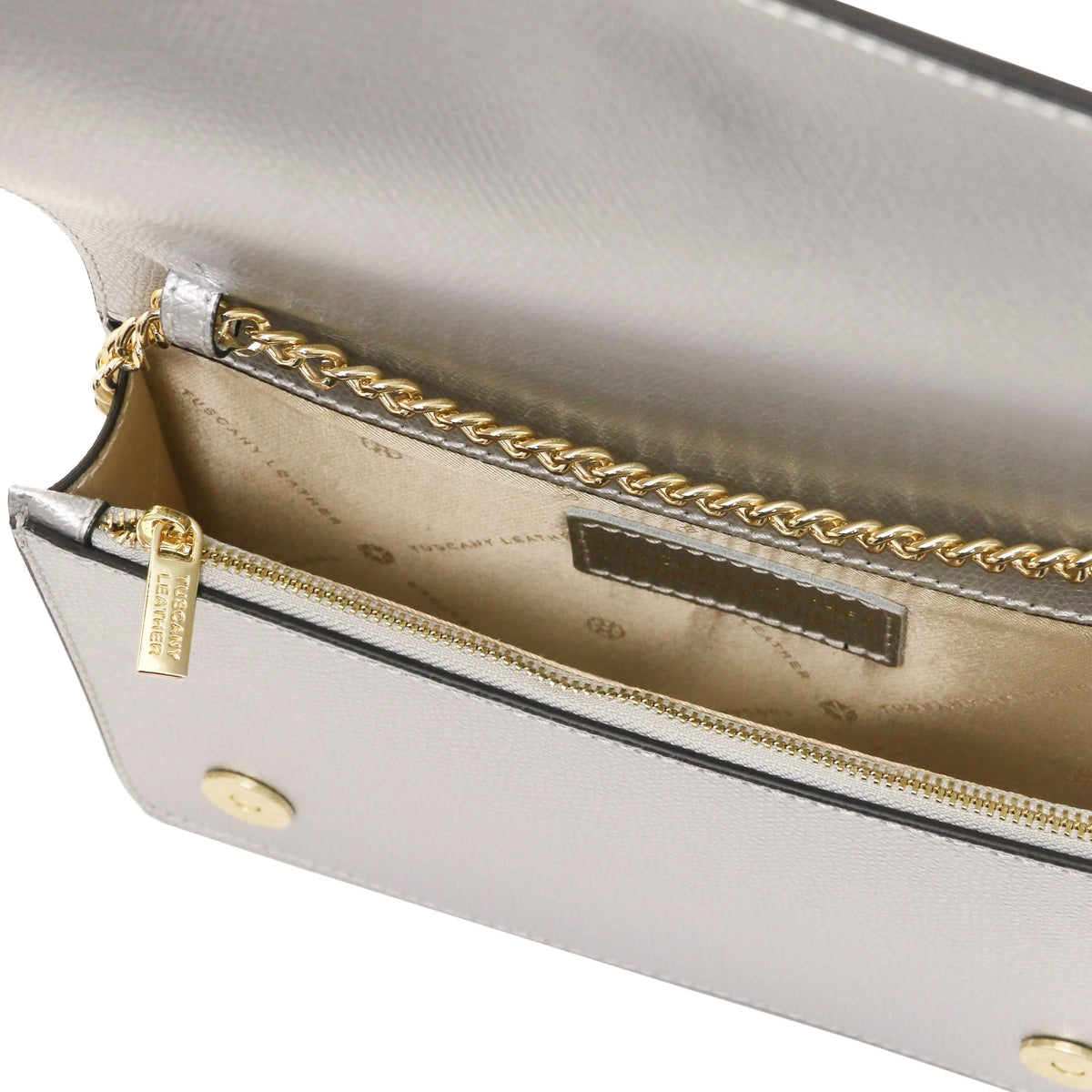 Close-up of a light gray leather clutch bag showing the beige interior, gold-tone chain trim, zipper with a gold-tone pull tab, and branded interior label.